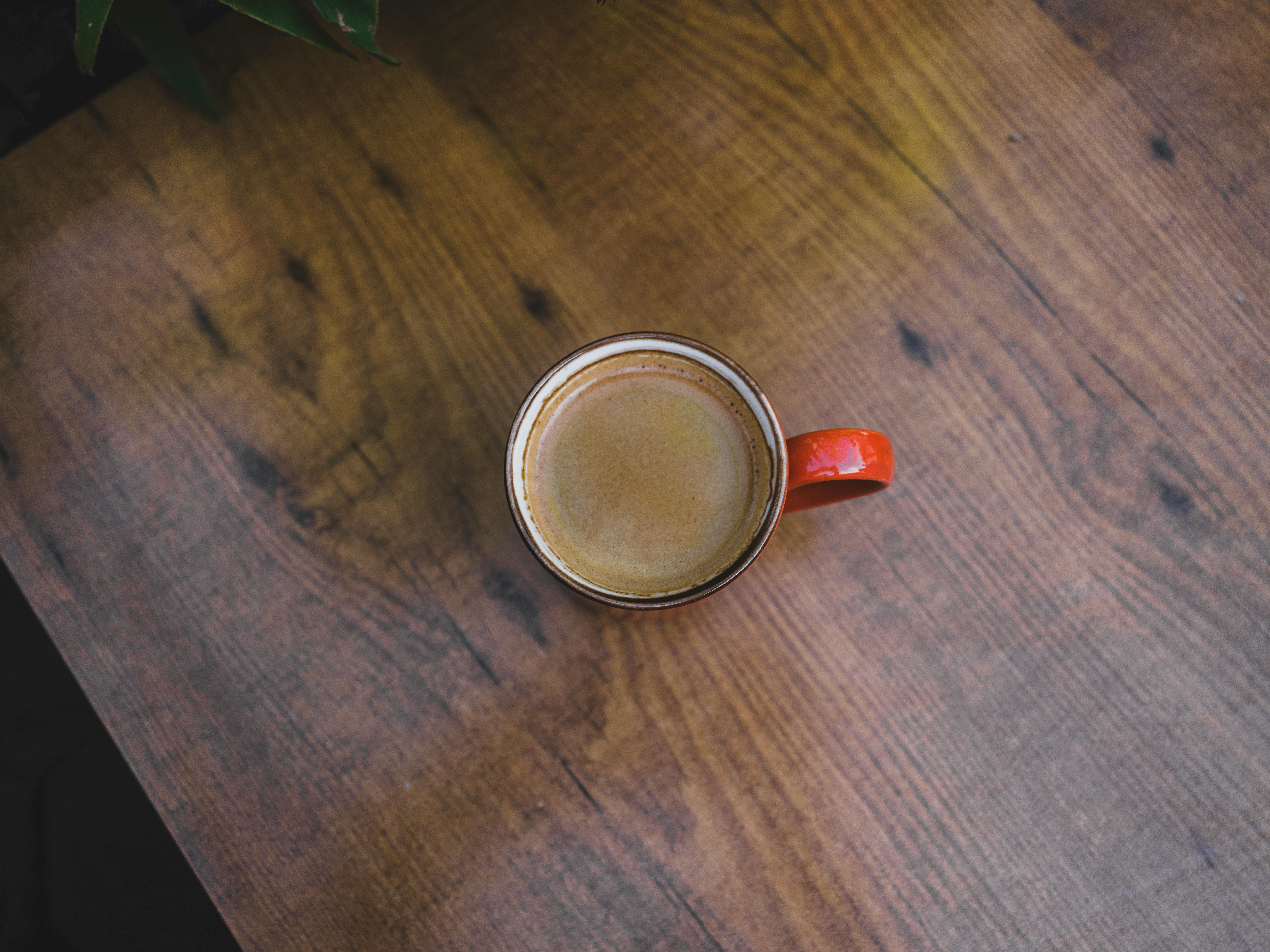 bezplatná Červený hrnek na kávu s horkým espressem na rustikálním dřevěném stole. Ideální pro útulný životní styl nebo ranní nápoje. Základová fotografie