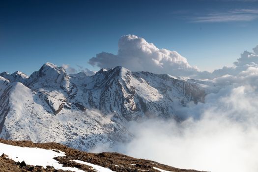 Breathtaking view of snow-covered mountains in Nepal, with clouds drifting by.