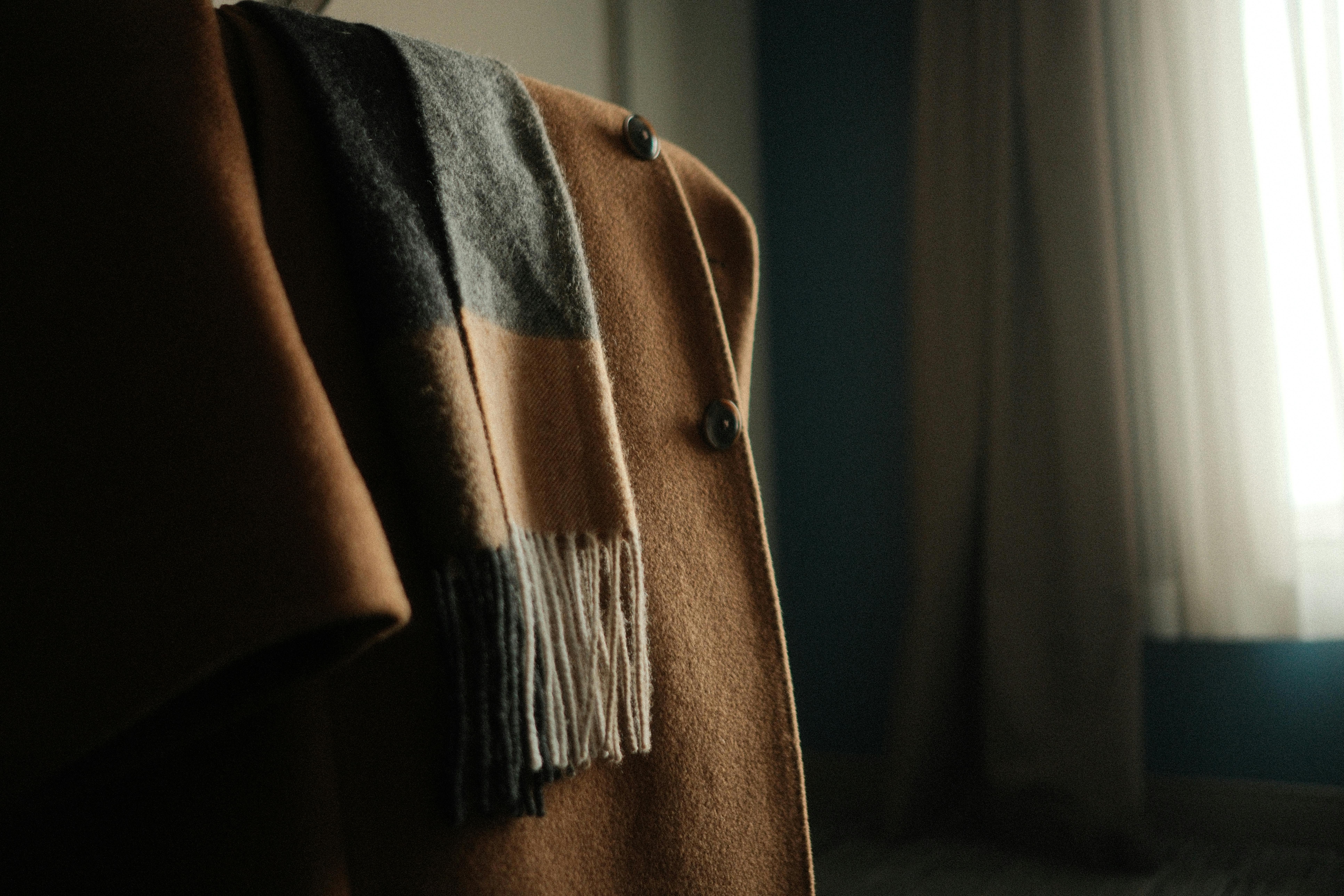 bezplatná Pohodlný kabát v velbloudí barvě s přehozeným vlněným šátkem, který v interiéru představuje zimní módu. Základová fotografie