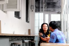 Two adults engaging in conversation in a stylish cafe with minimalistic decor.
