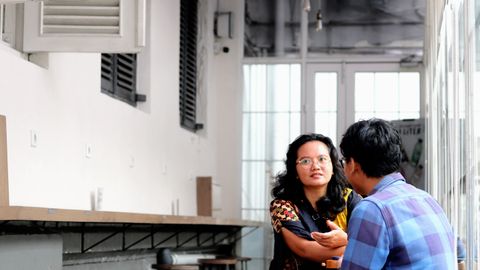 Two adults engaging in conversation in a stylish cafe with minimalistic decor.