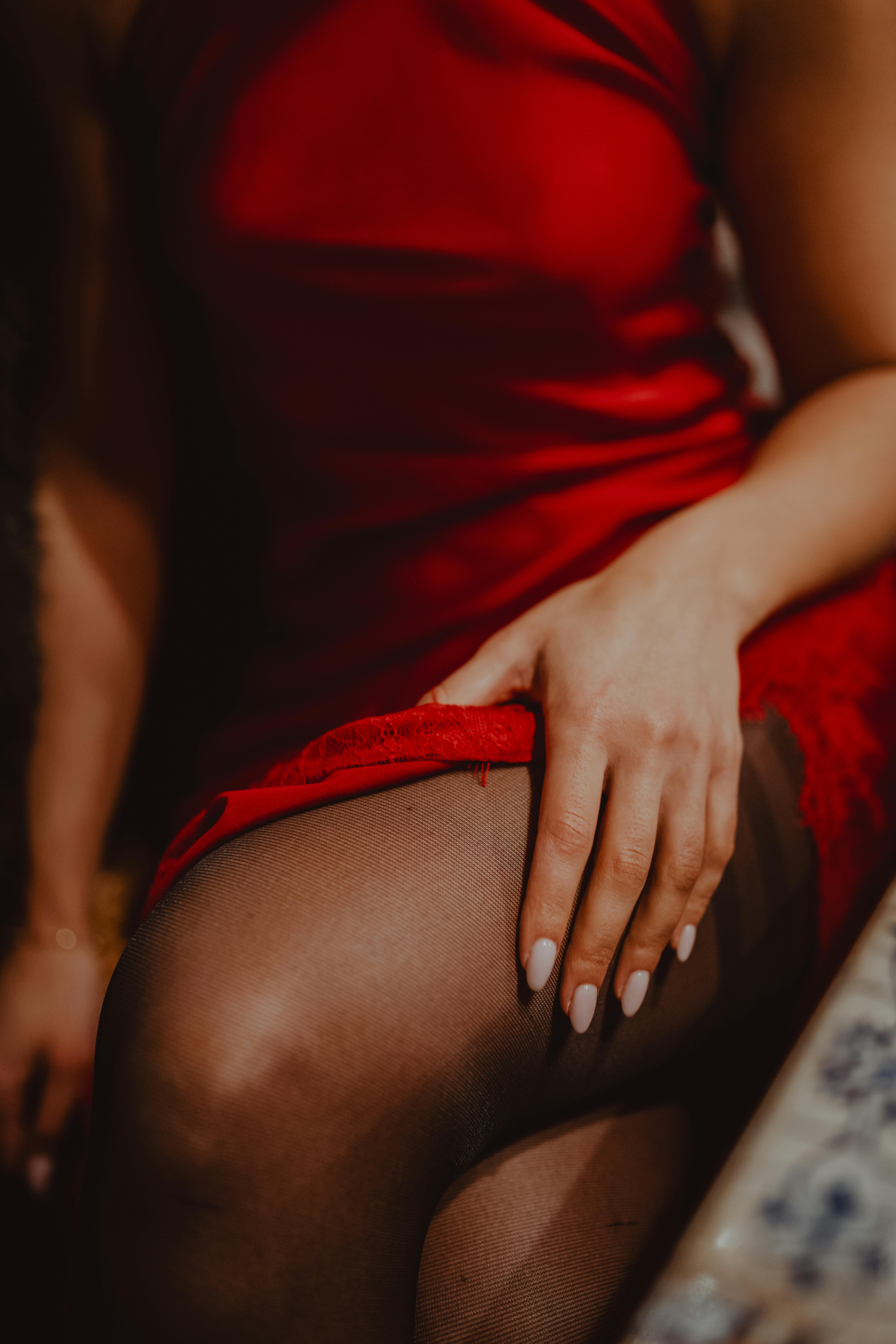 bezplatná Detailní záběr ženské ruky na červených šatech, vyjádření elegance a stylu. Základová fotografie