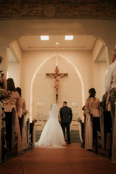 A beautiful wedding ceremony in a church with the bride and groom at the altar.