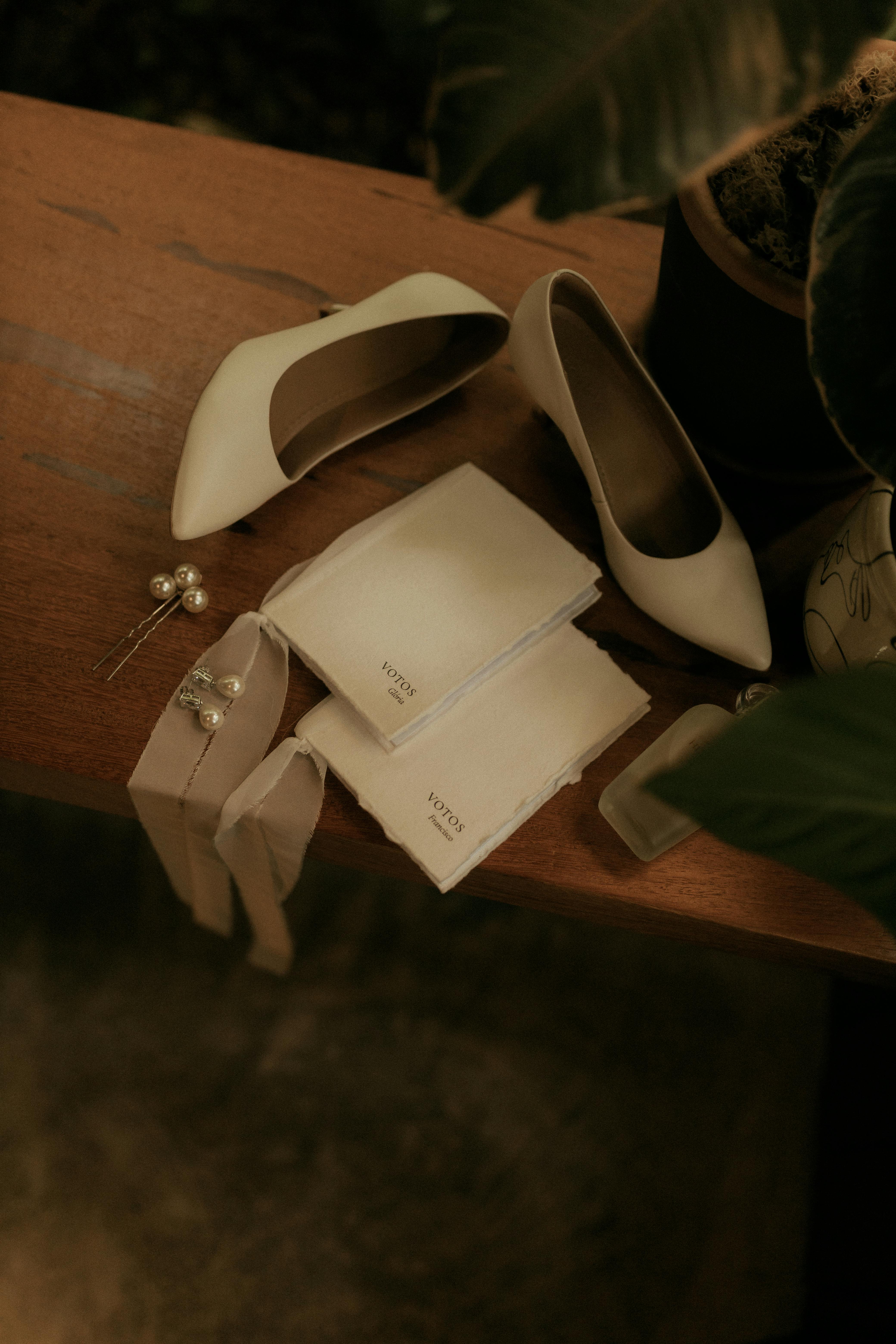 Kostenlos Auf einem Holztisch sind Hochzeitsaccessoires wie Schuhe und Papeterie arrangiert. Stock-Foto