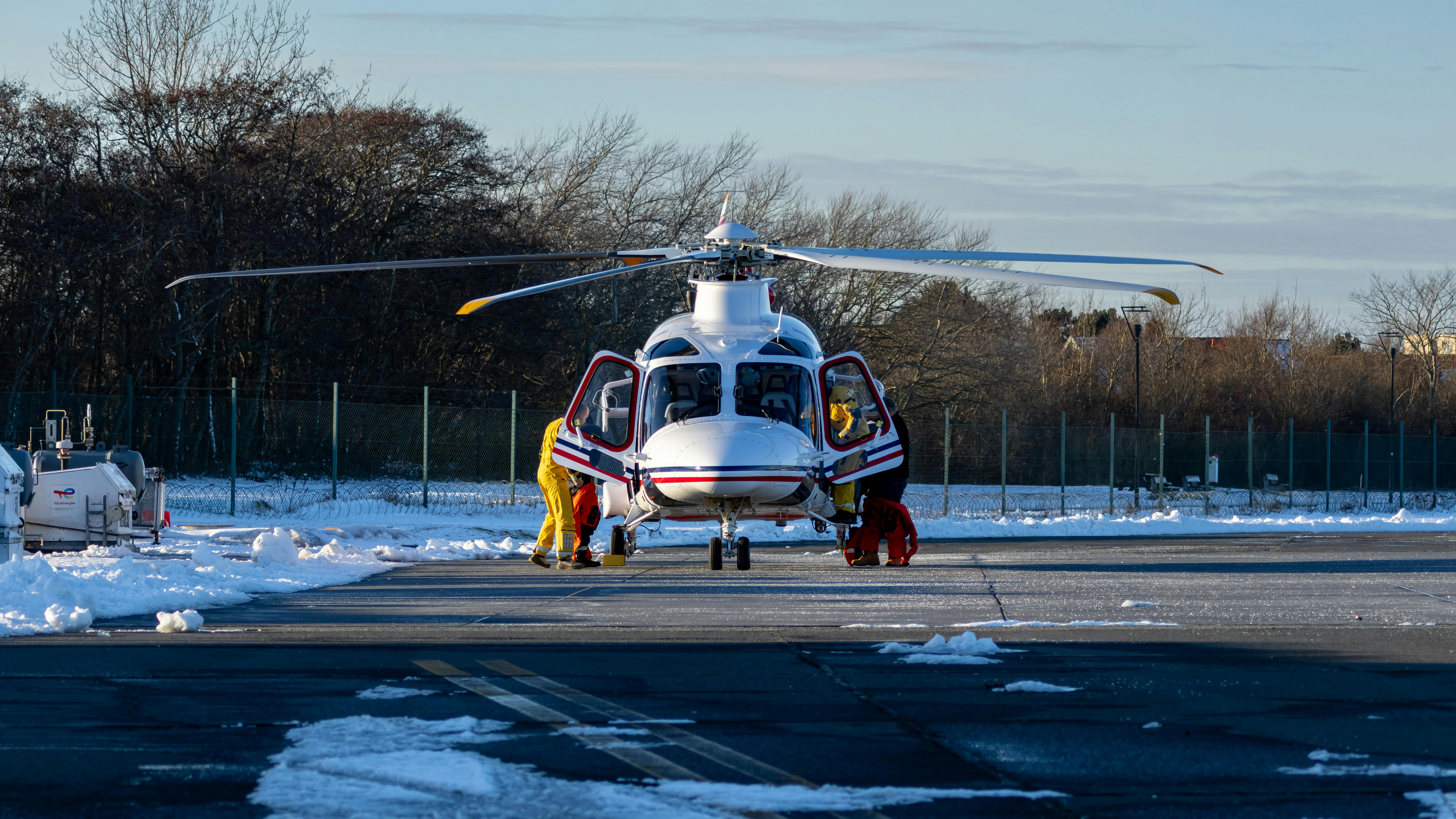 Ilmainen Helikopteri lumisella kiitotiellä miehistön valmistautuessa lentoon. Kuvapankkikuva
