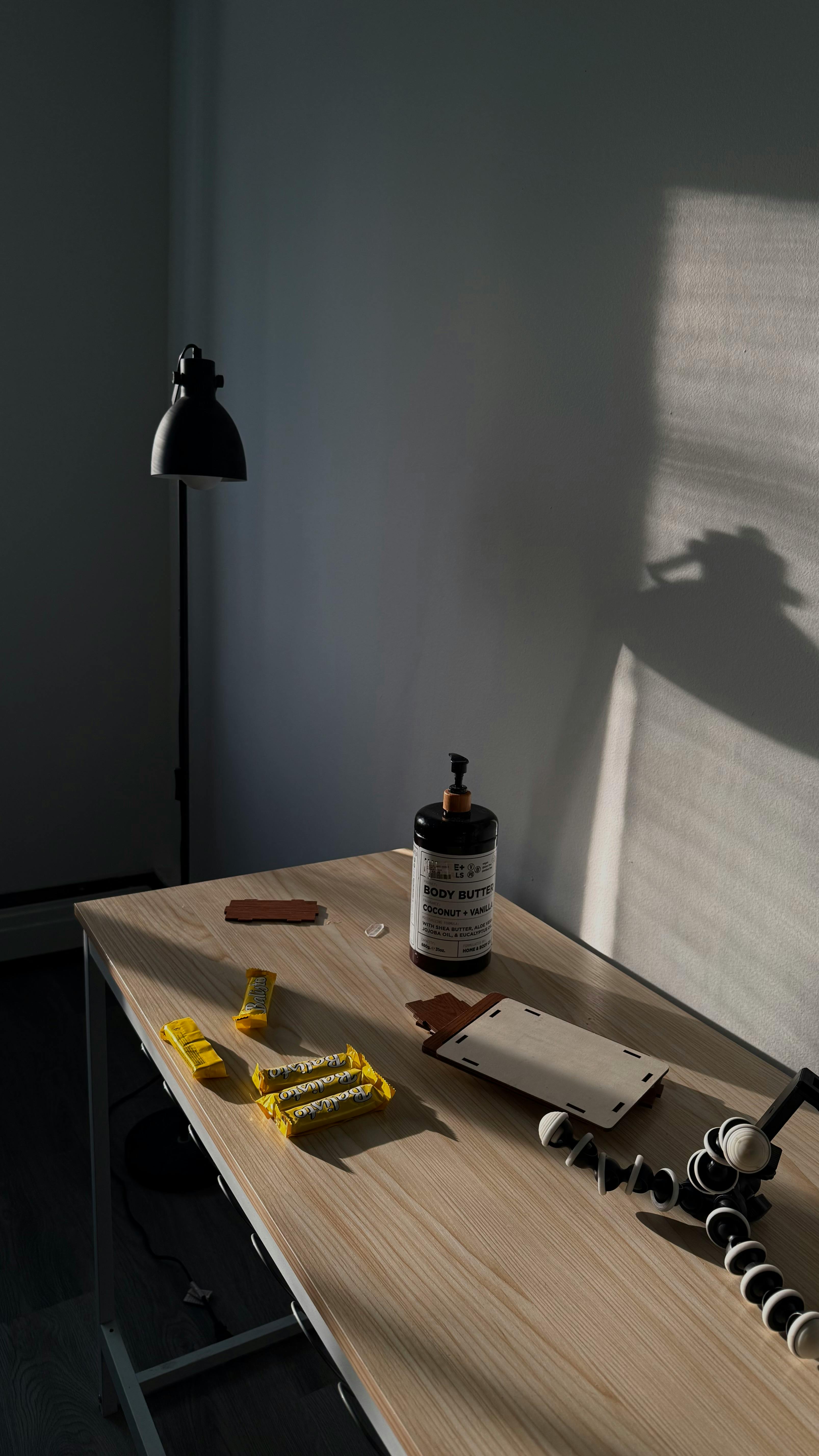 Free A minimalist office desk with a lamp, shadows, and assorted stationery in natural light. Stock Photo