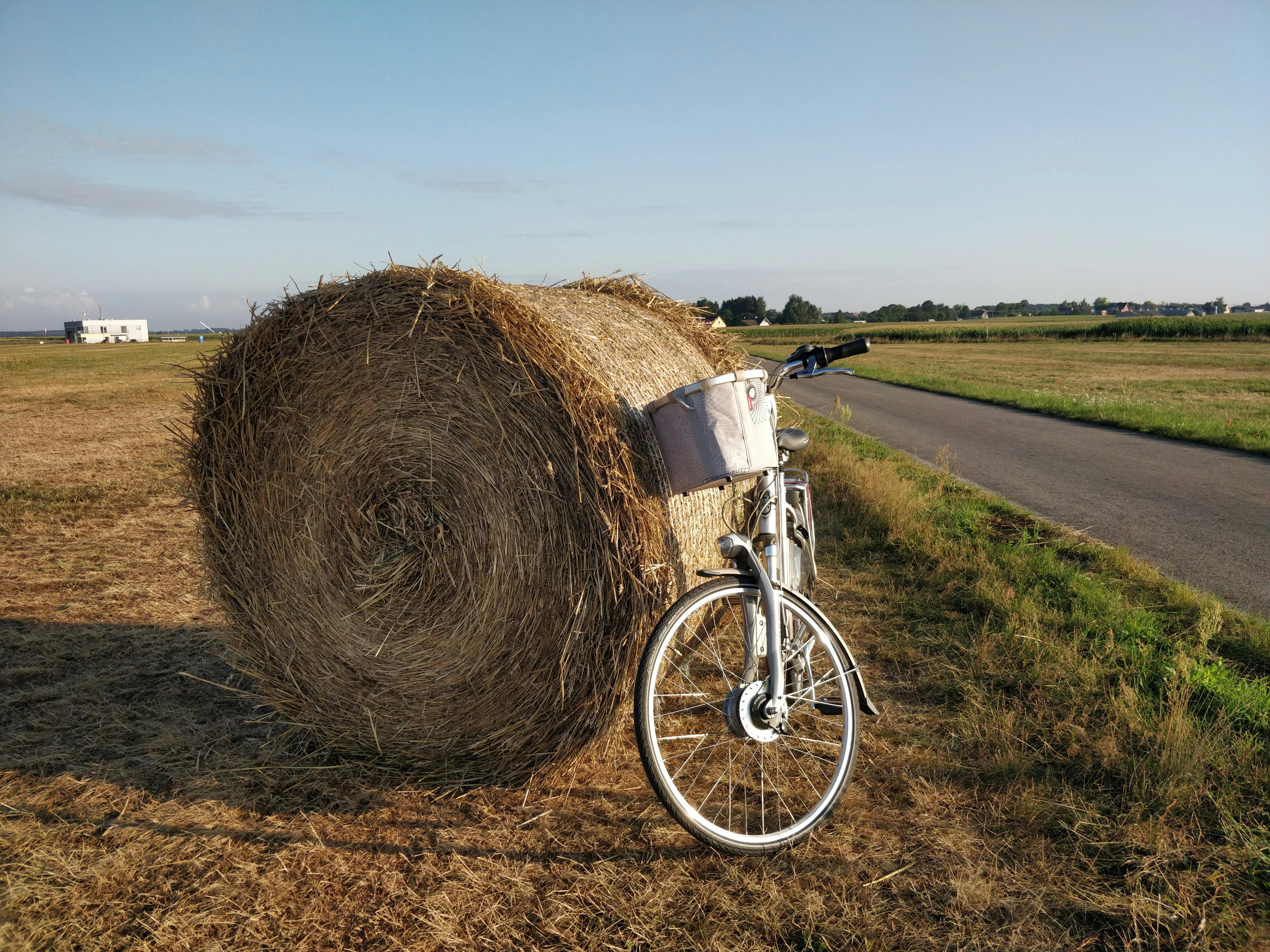 Gratis En cykel læner sig på en stor høballe på en malerisk mark i dagtimerne. Lagerfoto
