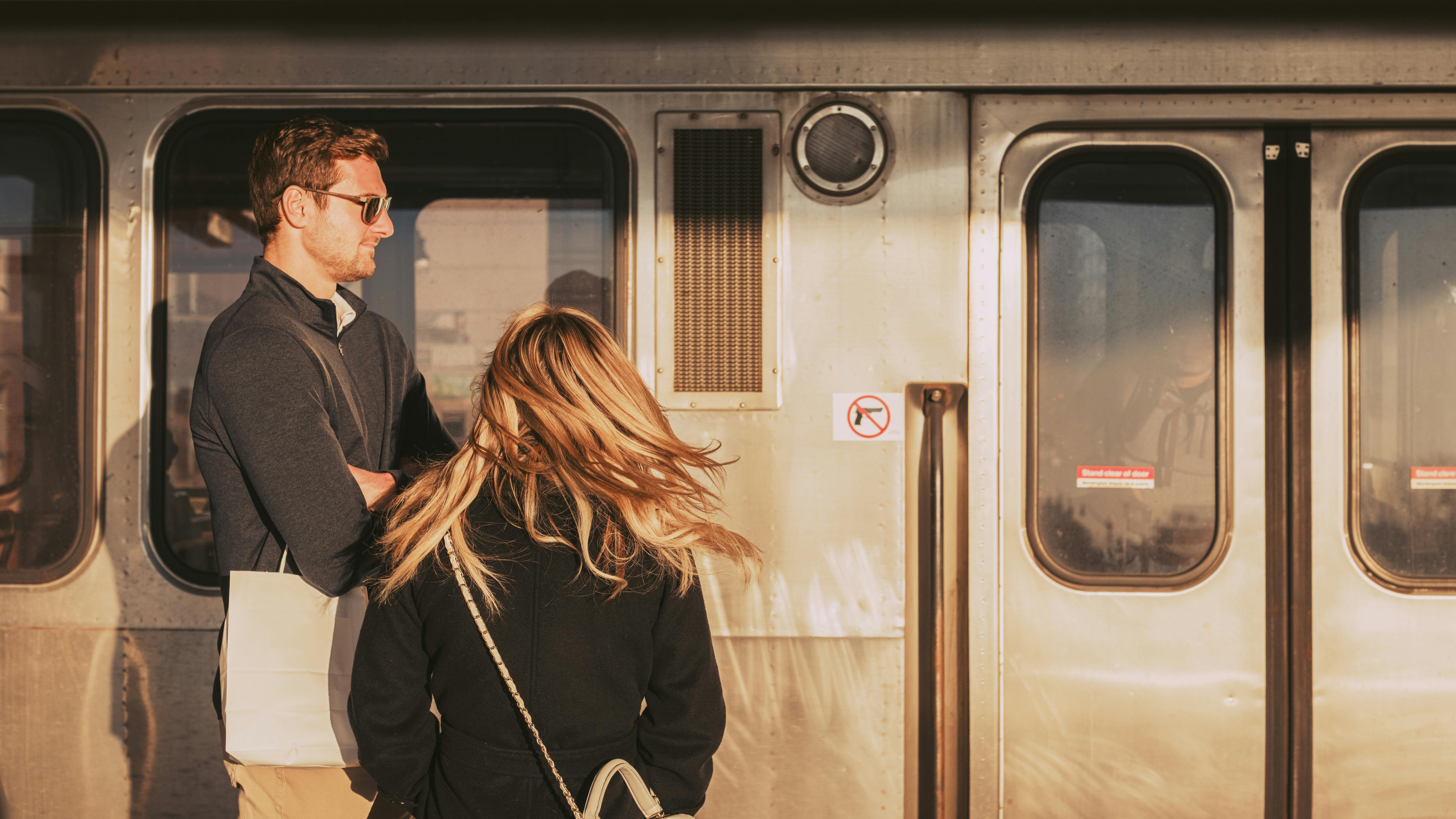 Miễn phí Hai hành khách đứng cạnh một toa tàu lúc hoàng hôn, được tắm mình trong ánh sáng vàng ấm áp, tạo nên một khung cảnh du lịch thanh bình. Ảnh lưu trữ