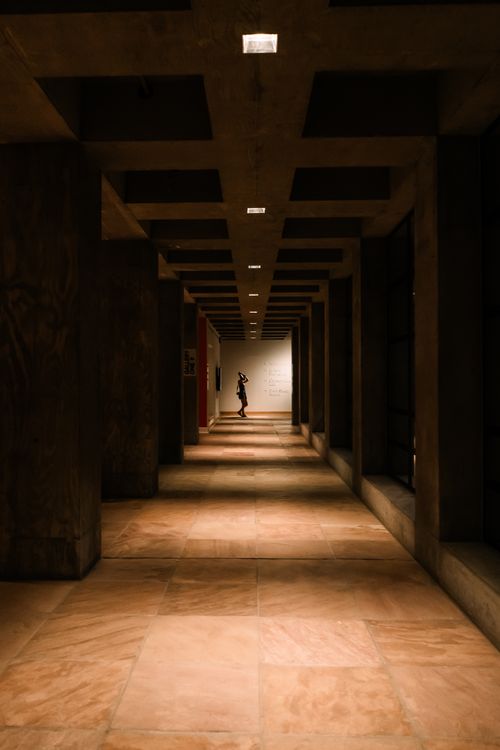 Free A moody, dimly lit corridor with a solitary figure standing at the end, Tempe, AZ. Stock Photo