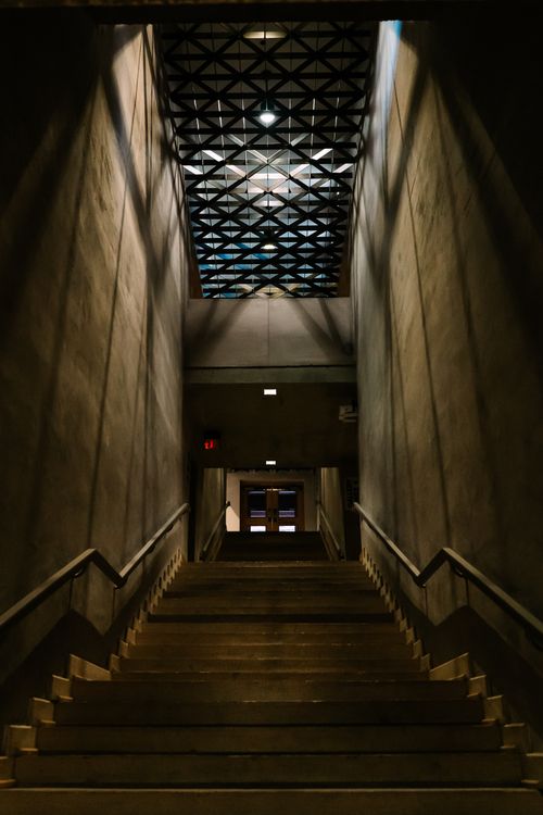Free A dimly lit staircase with geometric ceiling patterns, creating a dramatic atmosphere indoors. Stock Photo
