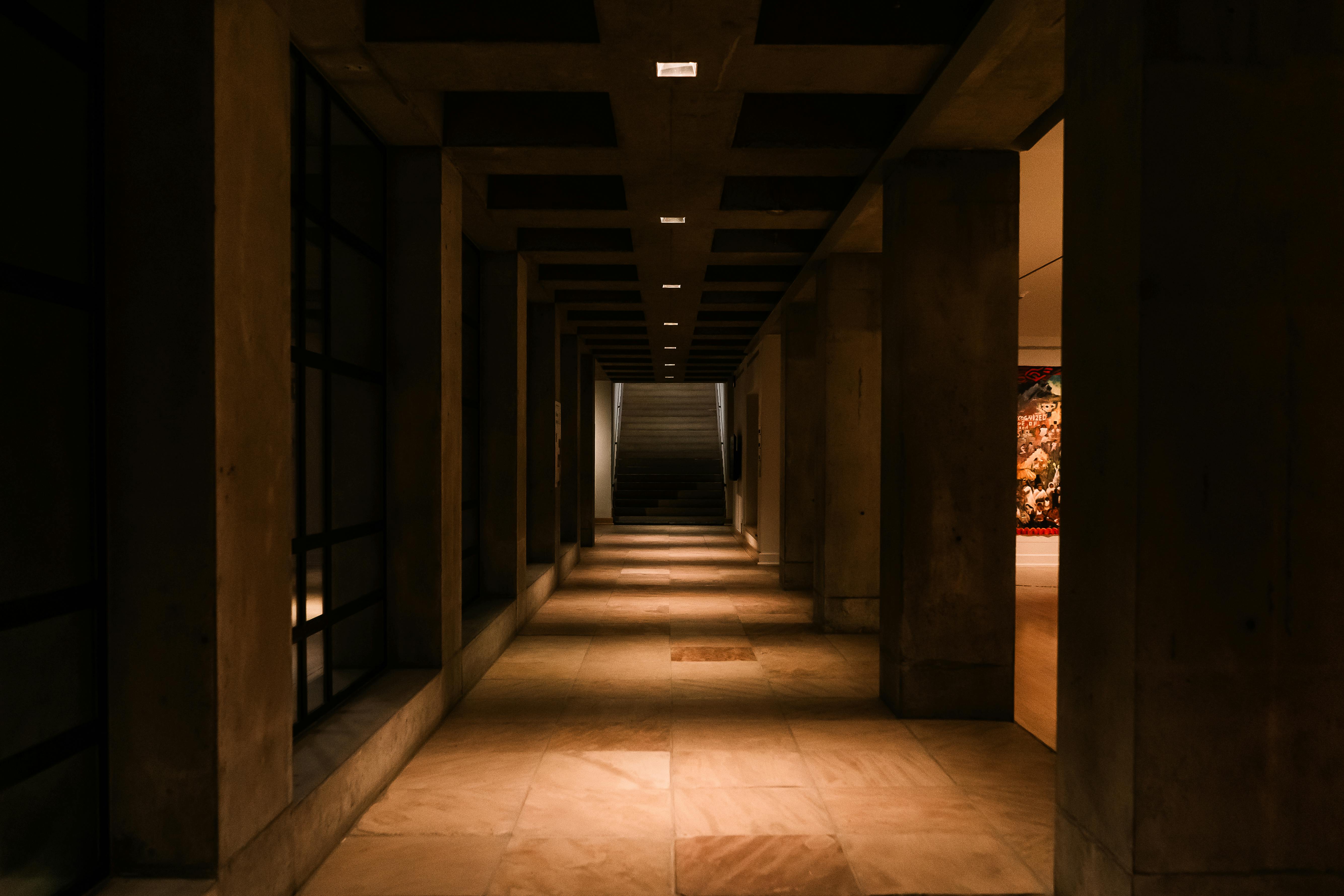 gratis Sfeervol perspectief van een schemerig verlichte gang met betonnen pilaren en warme verlichting. Stockfoto