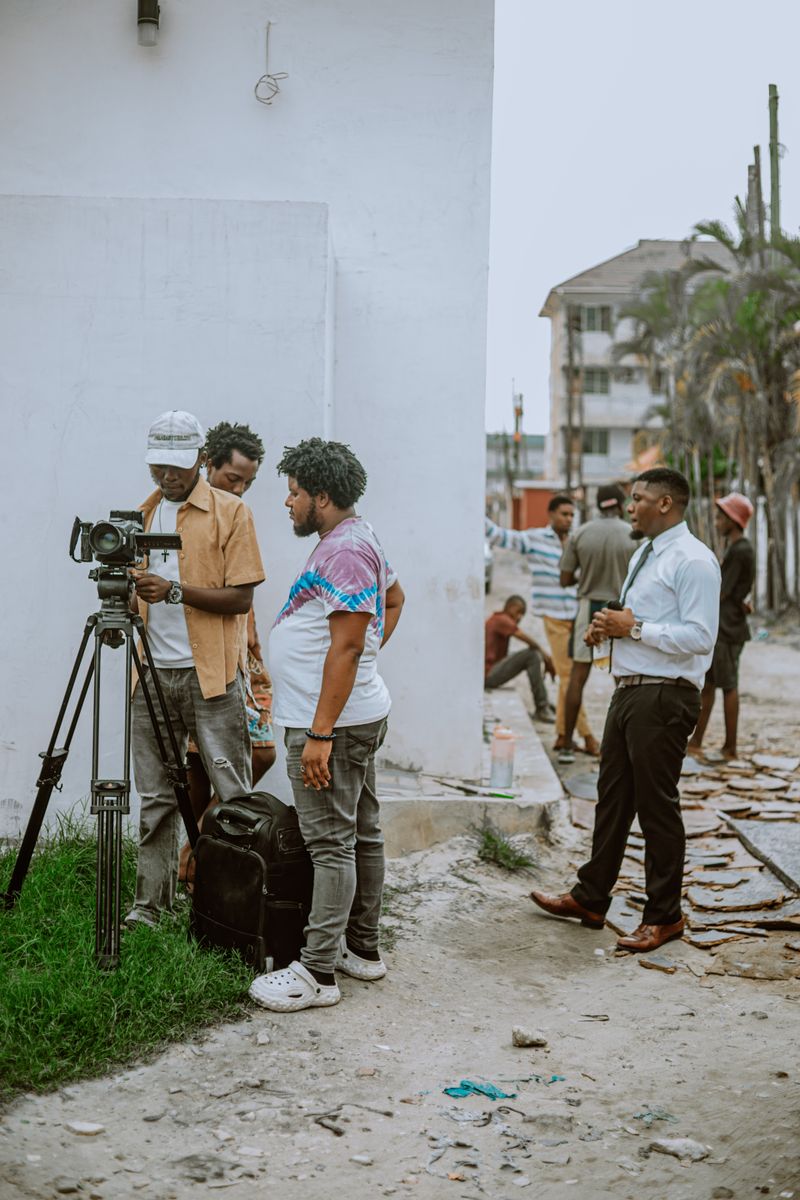 A diverse group of filmmakers setting up equipment outdoors for a scene.