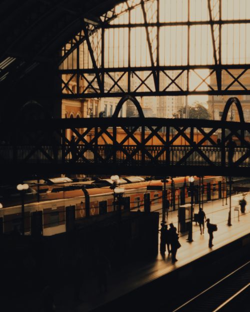 Free Silhouettes of people at a busy São Paulo train station during sunset, creating a warm and dramatic scene. Stock Photo