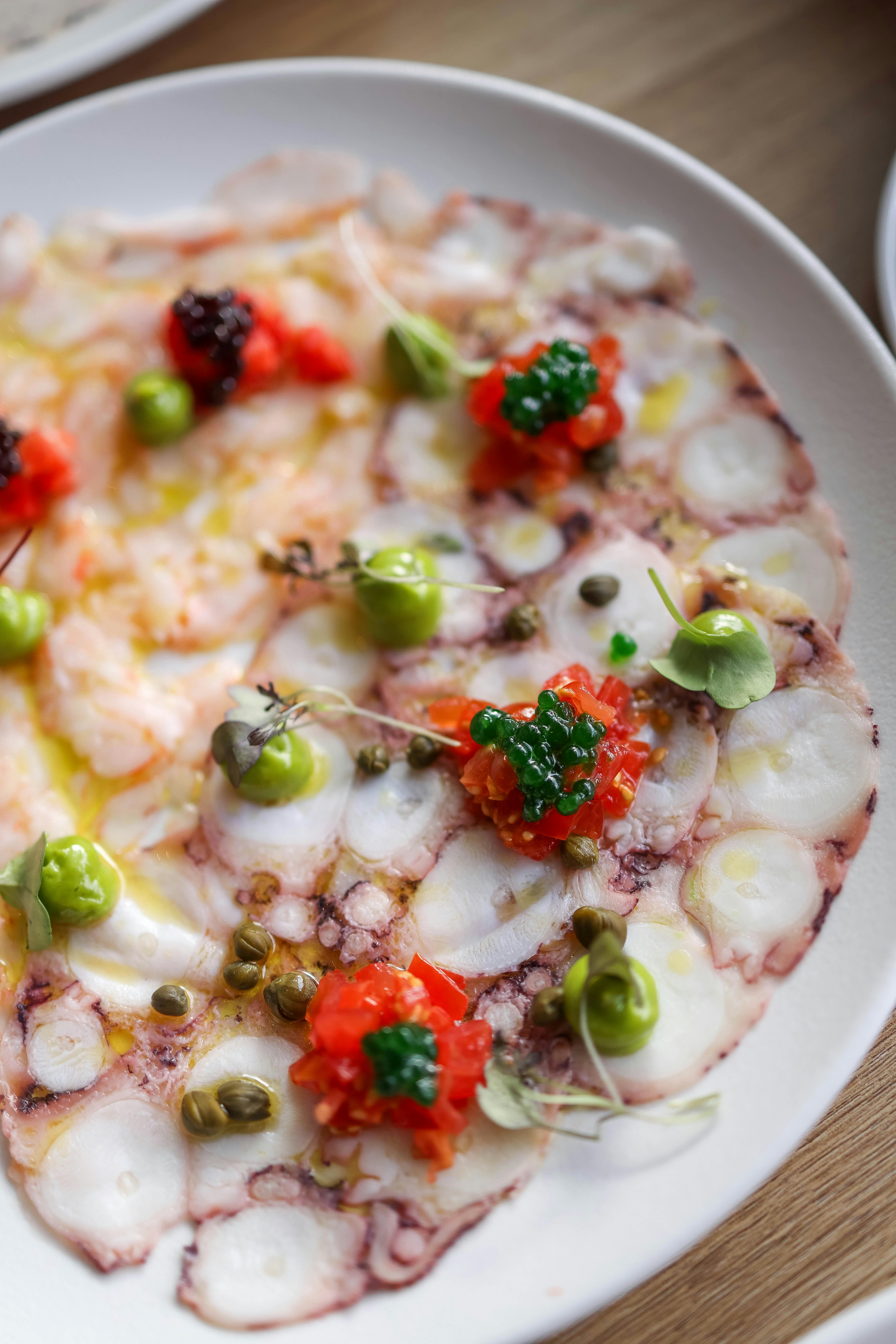 Exquisite octopus carpaccio garnished with vibrant sauces and seasonings, offering a gourmet dining experience.