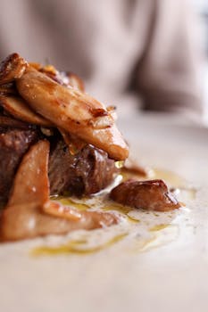 Delicious close-up of a steak topped with sautéed mushrooms in a creamy sauce.