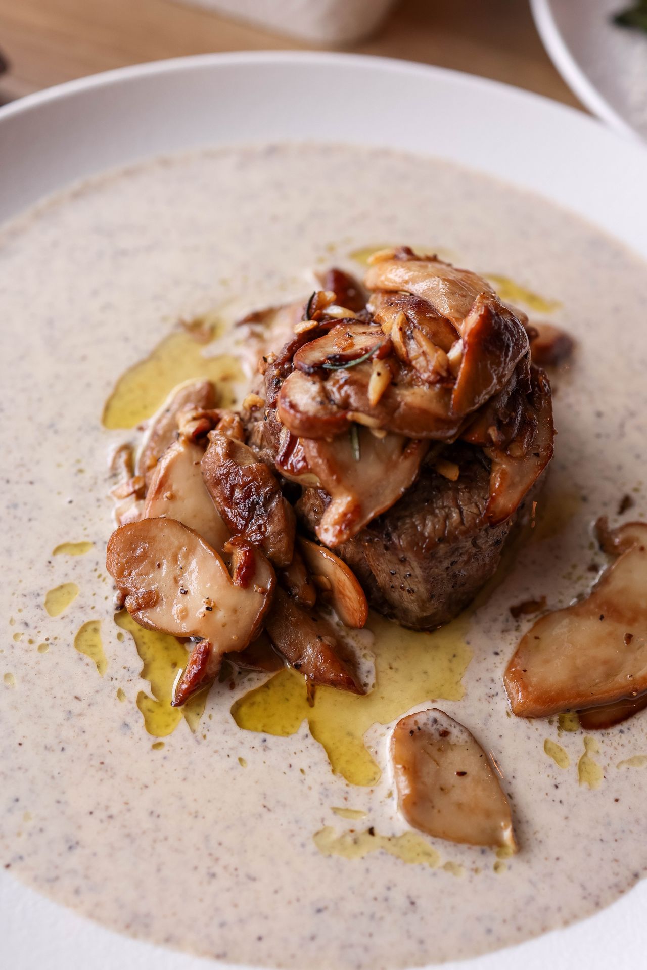 Beef fillet accompanied by sautéed mushrooms and creamy pan sauce plated elegantly