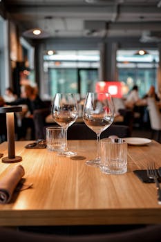A beautifully set restaurant table with glasses and napkins in a modern indoor setting.