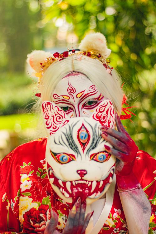 Free Colorful and artistic makeup with traditional kimono outdoors, holding decorative mask. Stock Photo