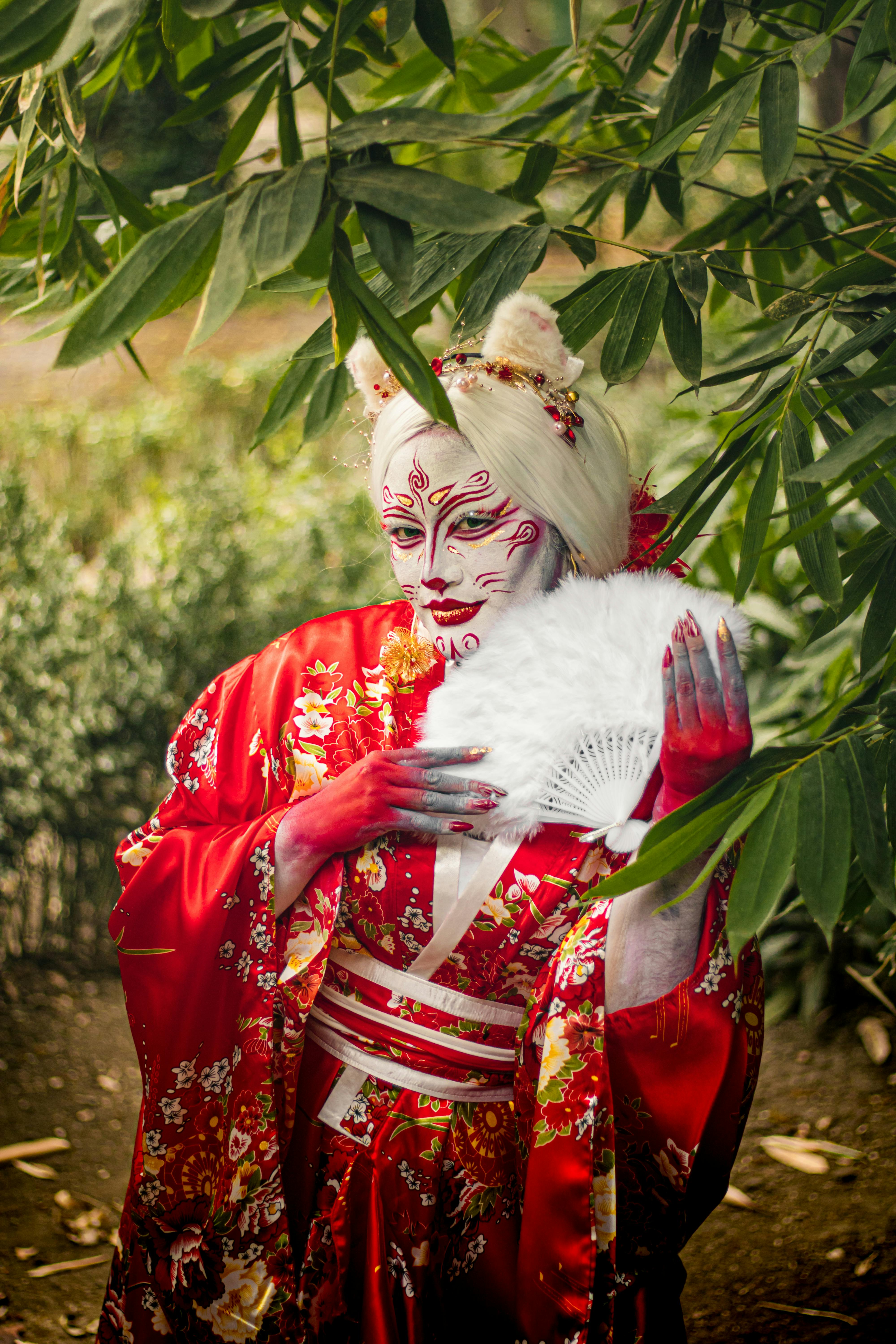 ฟรี ภาพถ่ายเชิงศิลปะที่แสดงถึงชุดกิโมโนแบบดั้งเดิมและการแต่งหน้าแบบจัดเต็มในบรรยากาศสวนสาธารณะกลางแจ้ง คลังภาพถ่าย