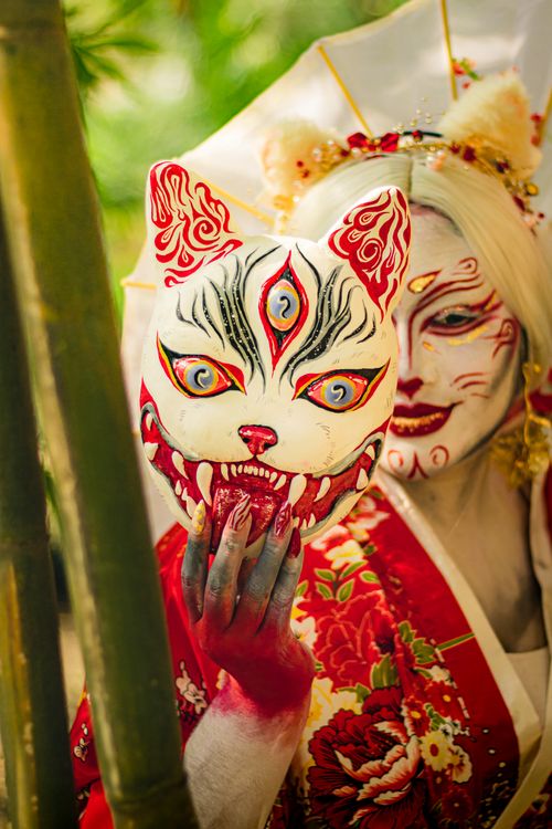 Free Colorful artistic portrait featuring a person in a kitsune mask and traditional red kimono. Stock Photo