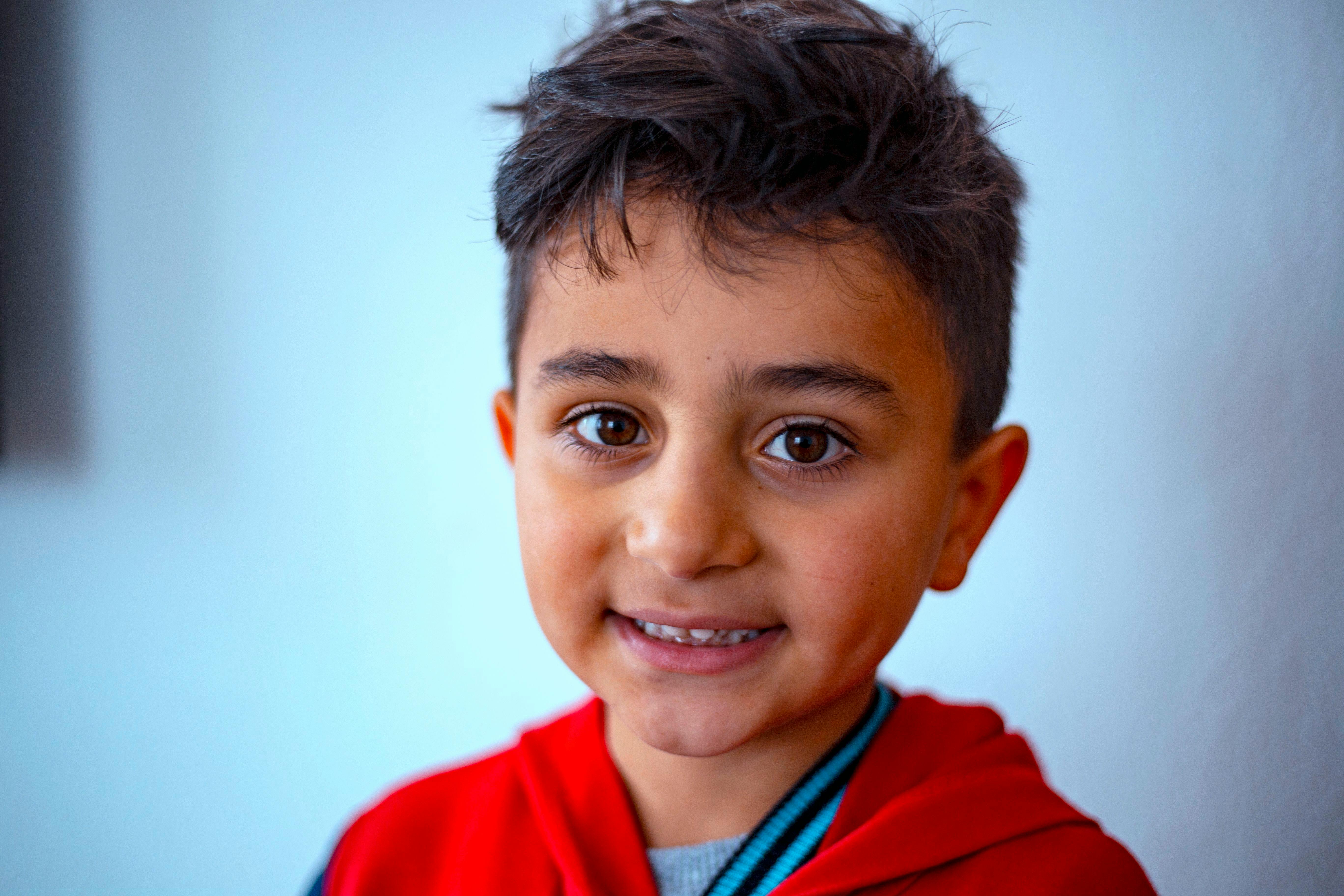 bezplatná Detailní záběr usmívajícího se dítěte uvnitř s červenou mikinou v Niğde v Turecku. Základová fotografie