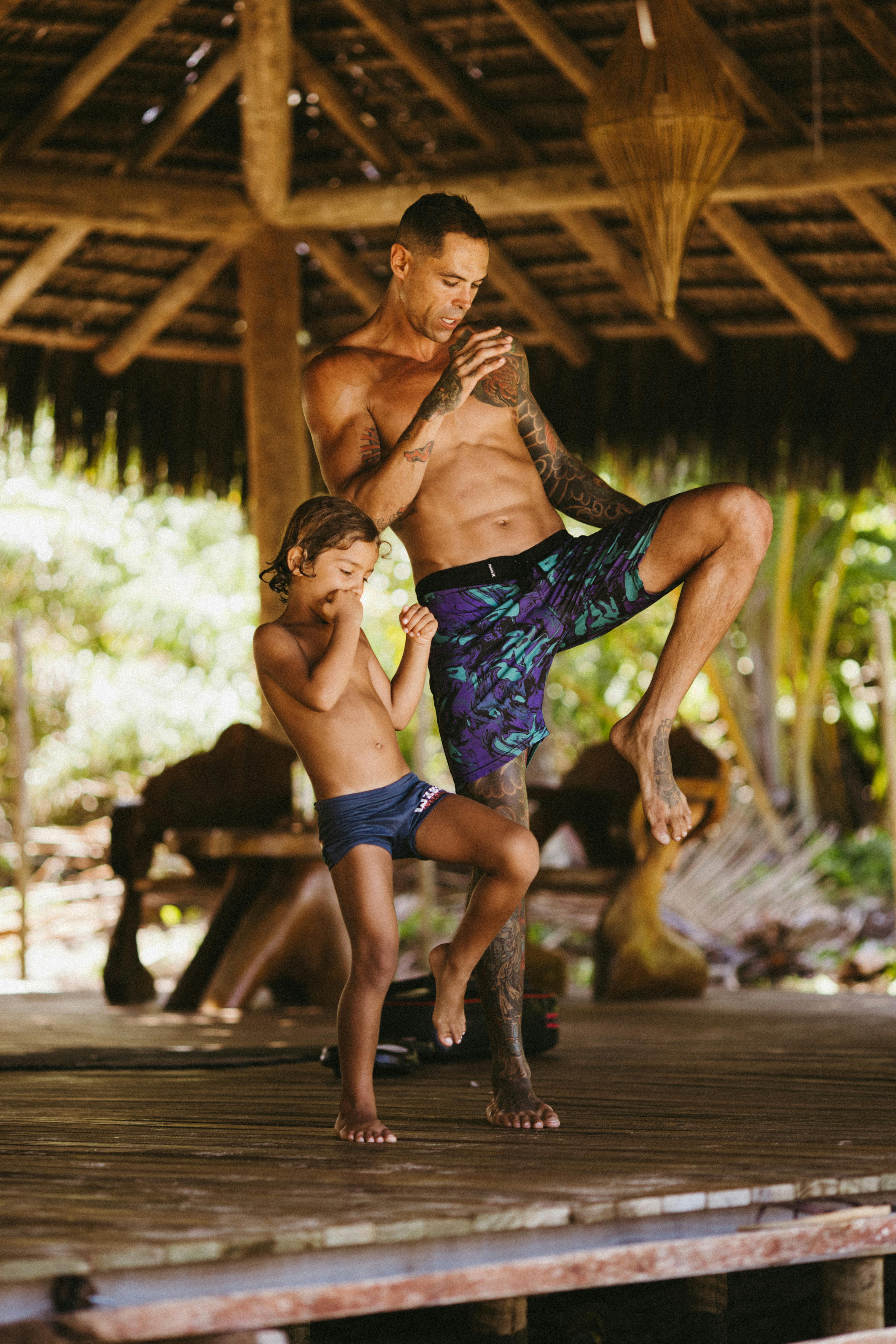 ฟรี พ่อและลูกชายฝึกโยคะด้วยกันบนระเบียงไม้ท่ามกลางธรรมชาติ ส่งเสริมความผูกพันในครอบครัวและสุขภาพที่ดี คลังภาพถ่าย