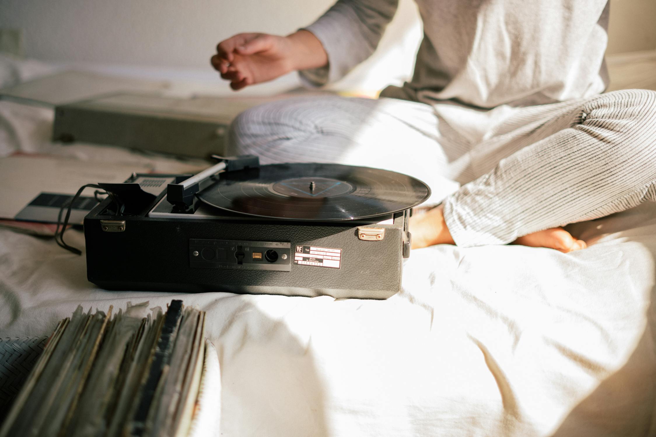 A record player sits on a bed.