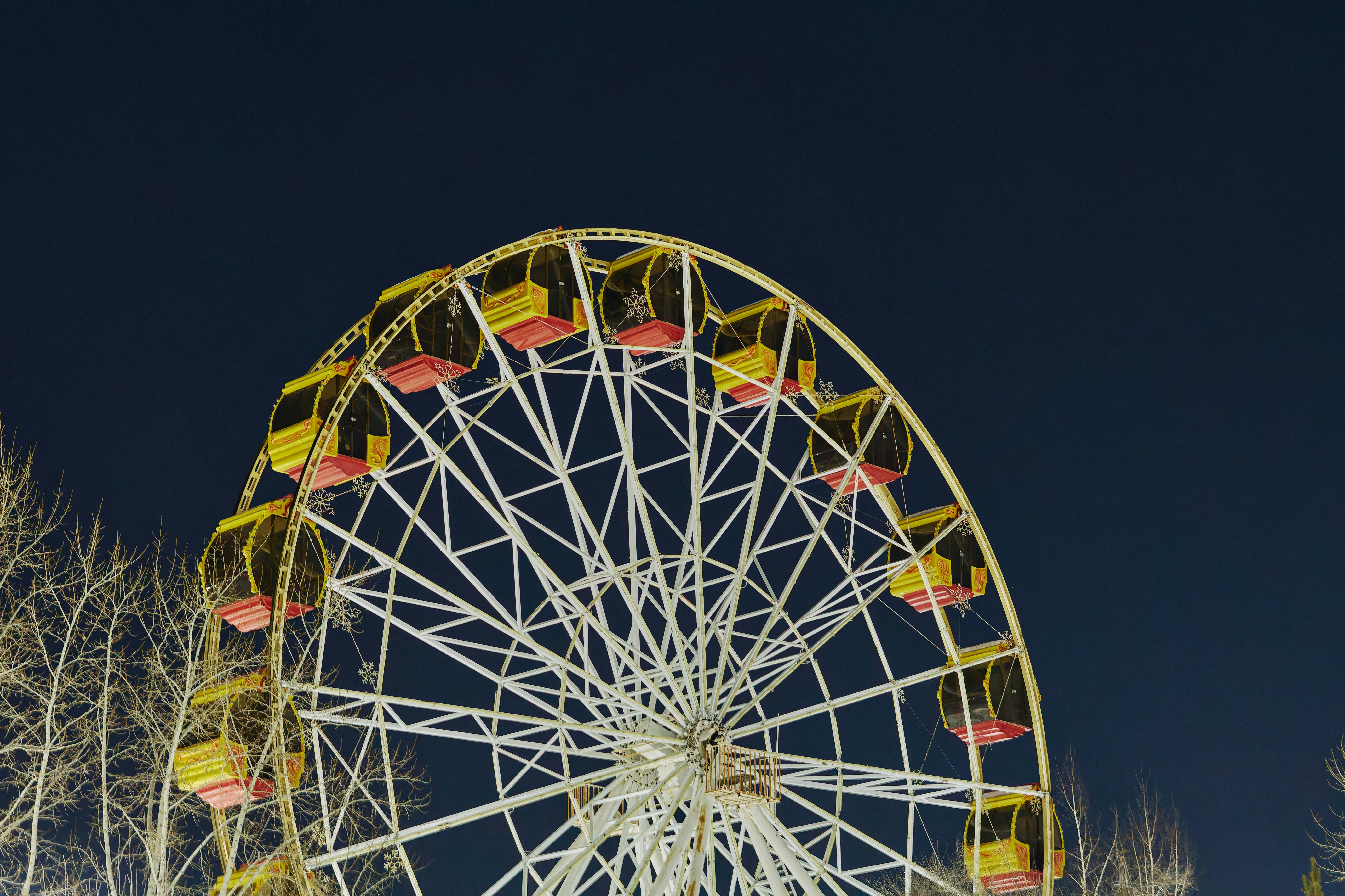 Bezpłatne Kolorowy diabelski młyn nocą, jasne światła na tle ciemnego nieba tworzą ożywioną, radosną atmosferę. Zdjęcie z galerii