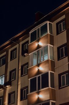 Mid-rise apartment building exterior with warm lighting and balconies captured at night.