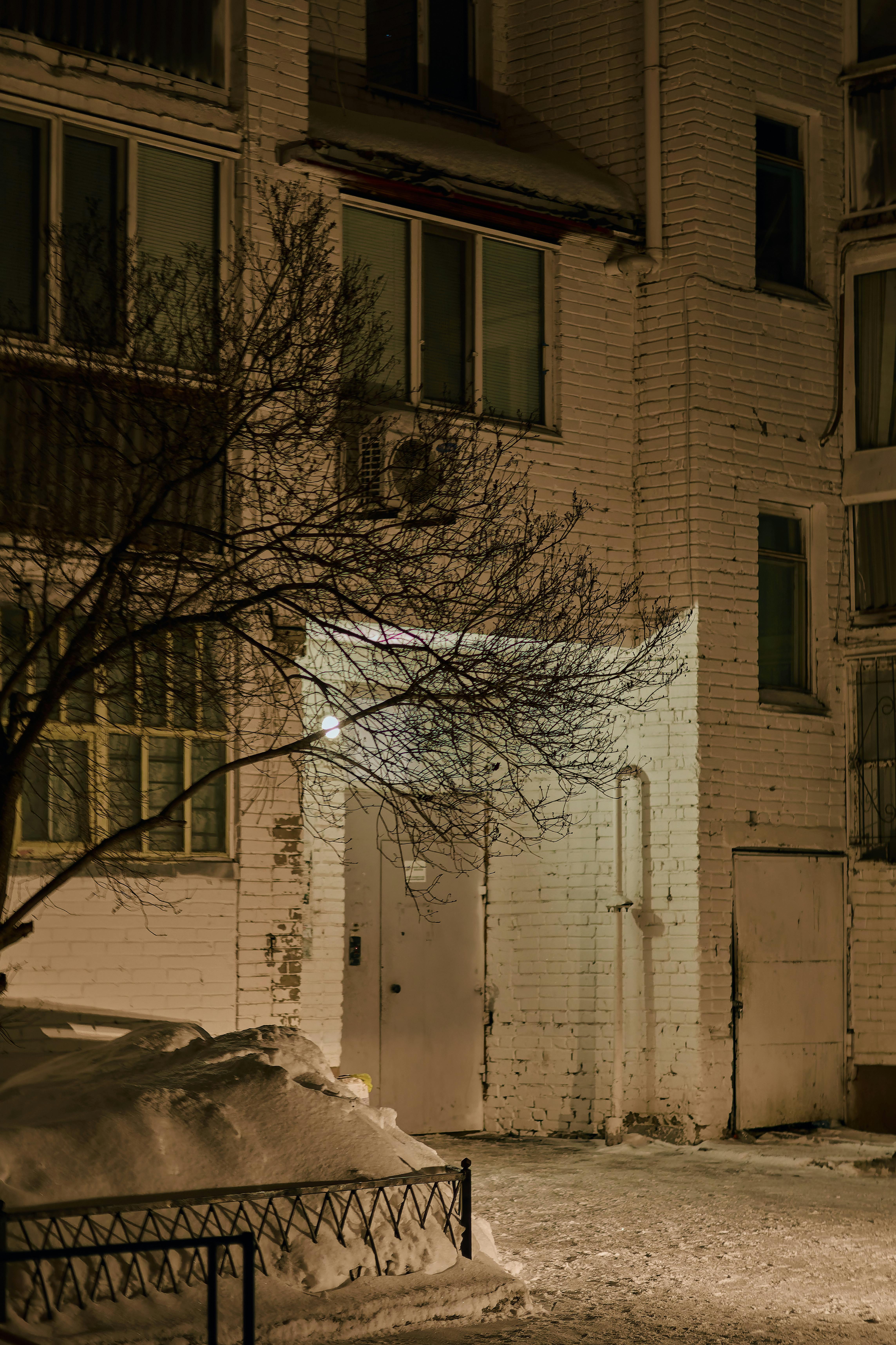 Kostenlos Beleuchteter Eingang eines schneebedeckten Stadtgebäudes bei Nacht. Stock-Foto