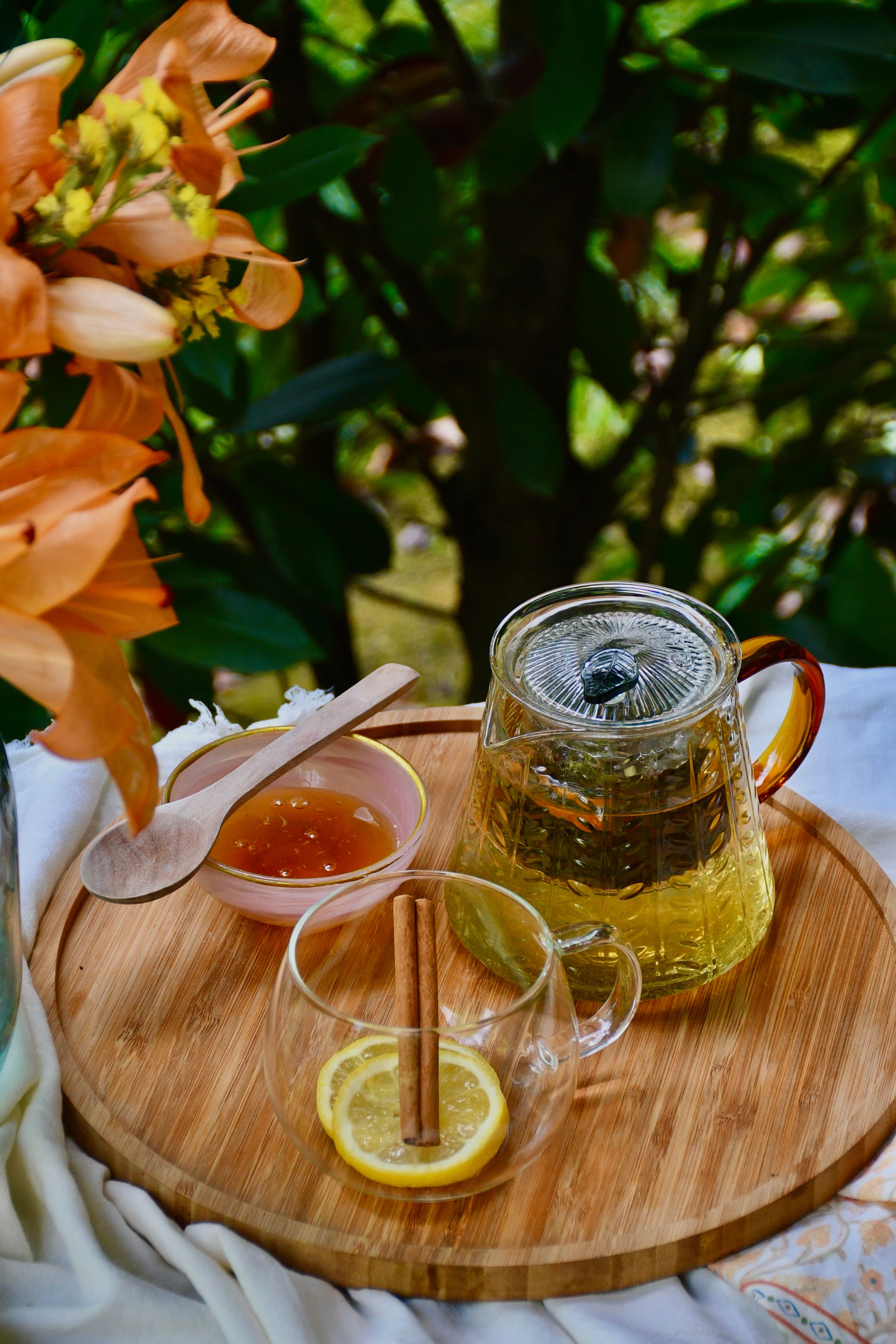 A warm herbal tea setup outdoors with honey, lemon, and flowers. Perfect for a cozy, nature-inspired experience.