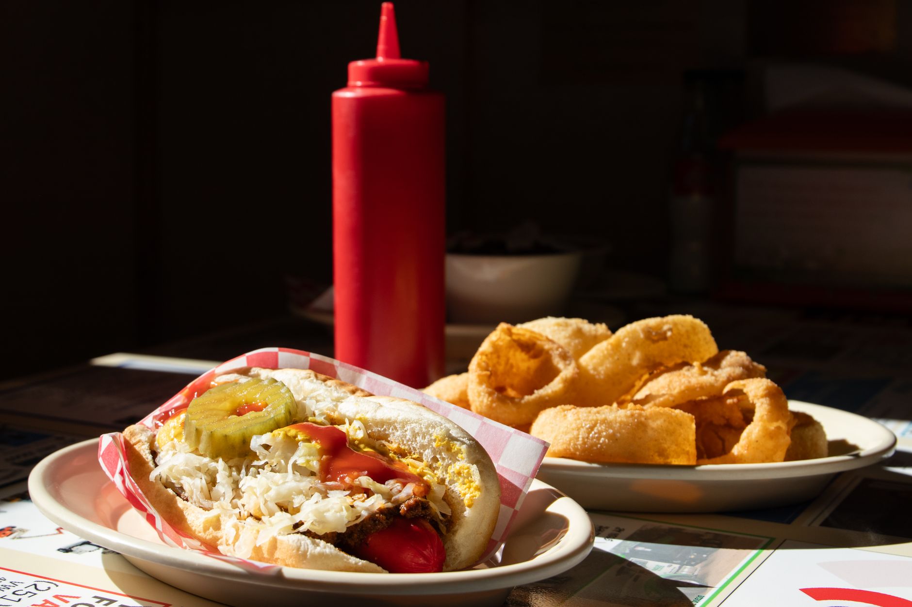 Close-up of a tasty hotdog with onion rings and condiments in an Alabama diner.