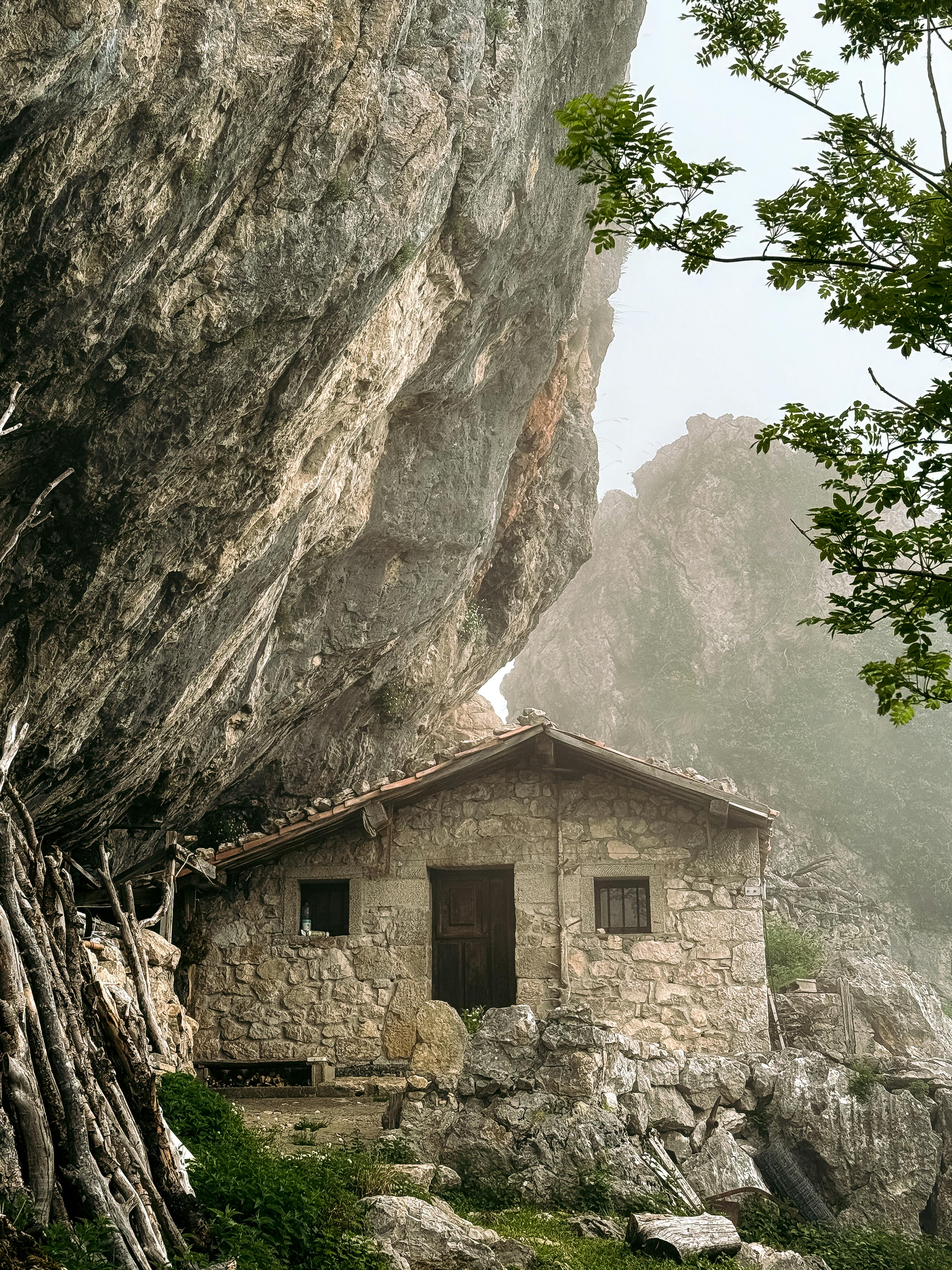 Ilmainen Viehättävä kivinen mökki kallion juurella Covadongassa, Espanjassa, luonnonkauneuden keskellä. Kuvapankkikuva