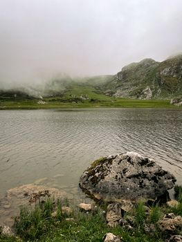 Serene lake with misty mountains in Covadonga, Spain, offering a tranquil natural landscape.