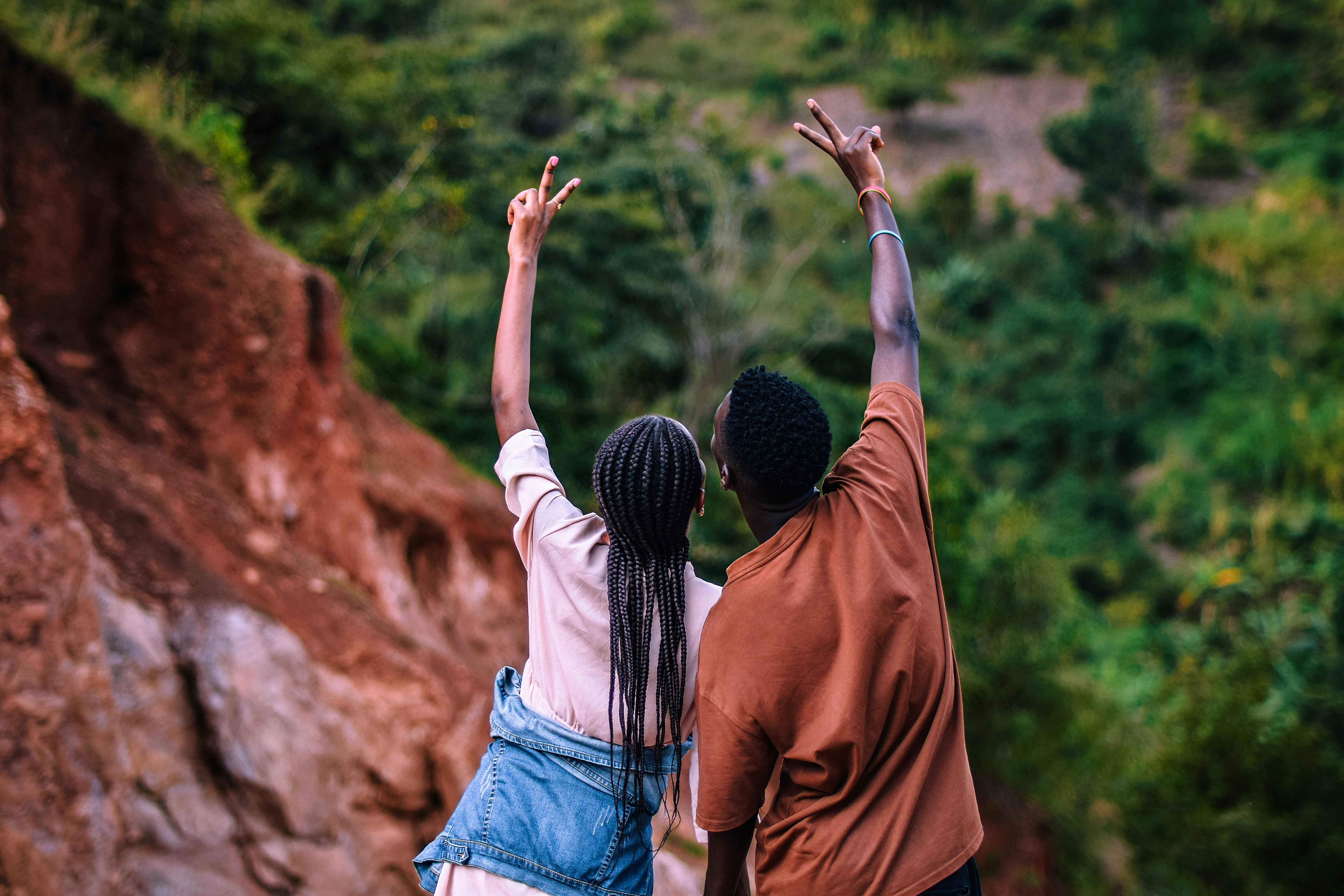 bezplatná Pár slaví v bujném venkovním prostředí a ukazuje znamení míru. Základová fotografie