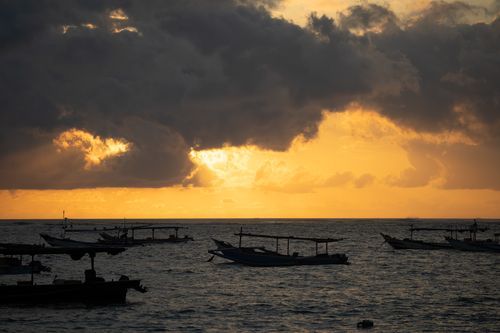 Free Dramatic sunset with boats silhouetted against golden sky in Bali, Indonesia. Stock Photo