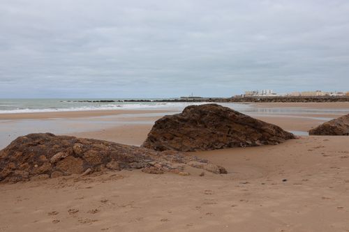 Free Serene coastal landscape of Cádiz with rocky beach and city views. Stock Photo