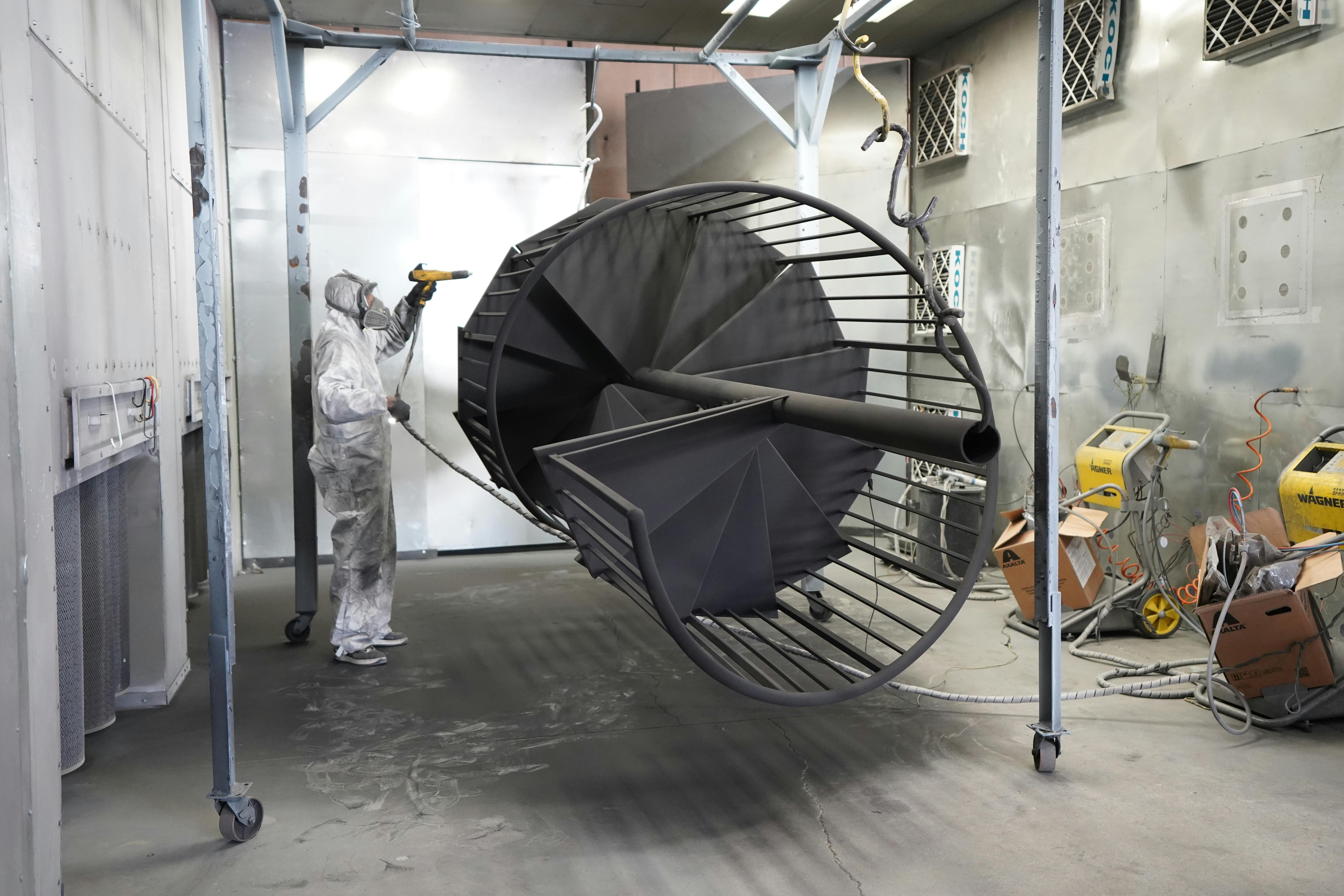 bezplatná Pracovník v ochranném vybavení nanáší ve spreji velkou průmyslovou kovovou konstrukci uvnitř. Základová fotografie