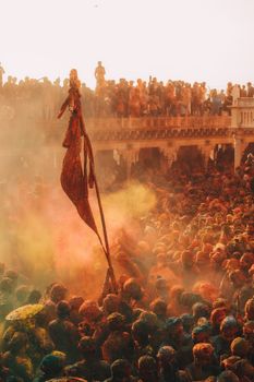 A vibrant crowd celebrating Holi, with colorful powders in the air, in Vrindavan, India.