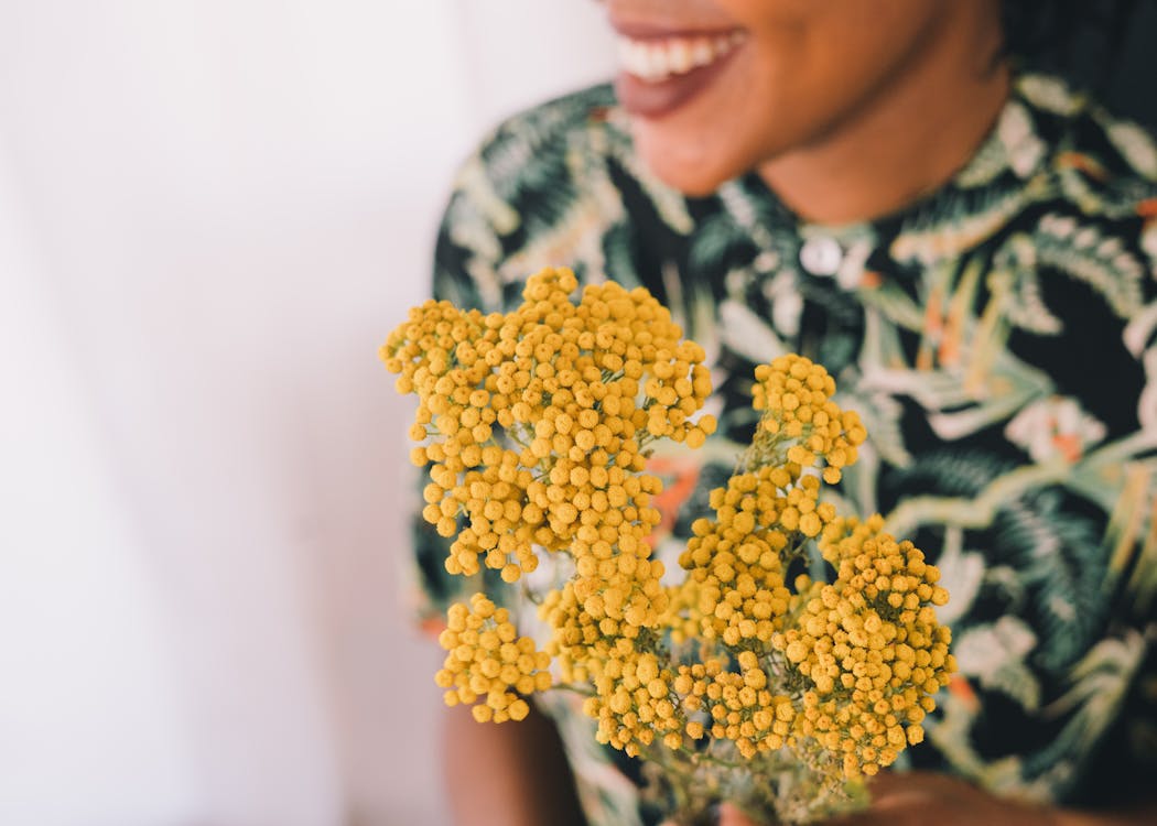 Woman in Black Floral Shirt Holding Yellow Flower Bouquet