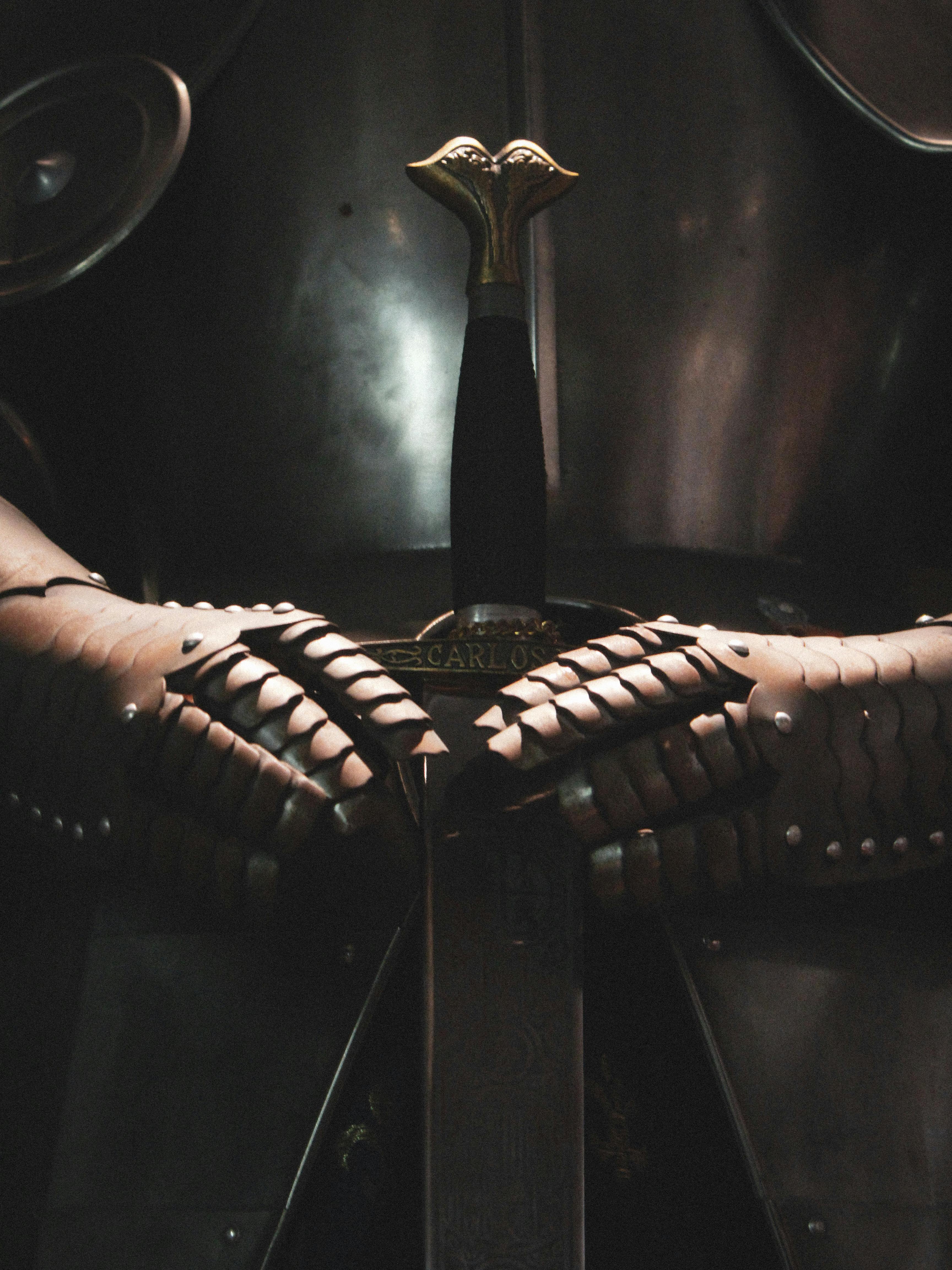 бесплатная Крупный план доспехов средневекового рыцаря, держащего меч, излучающего ощущение истории и мощи. Стоковое фото