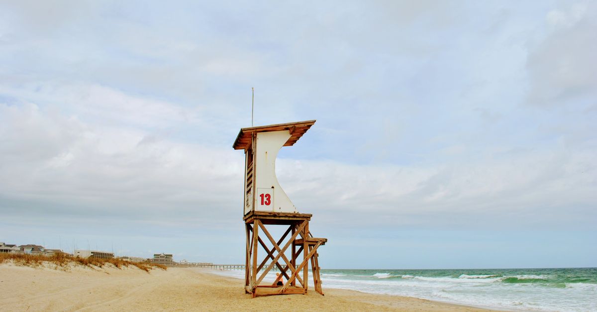 Peaceful beach scene in NC featuring a lifeguard tower and ocean waves.