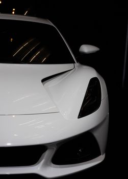 Close-up of a sleek white sports car with focus on the headlight and aerodynamic design.