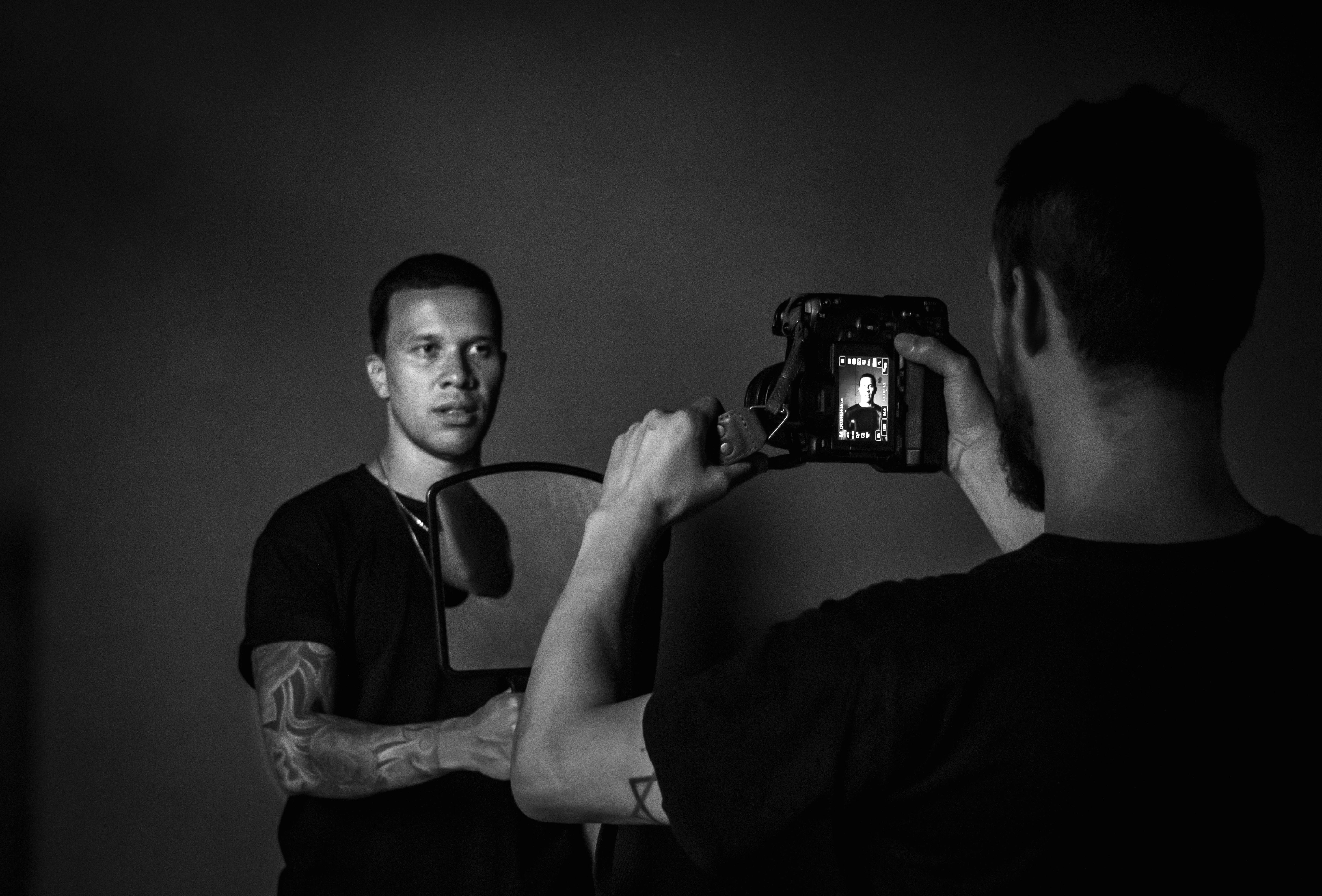 Gratis Scatto artistico monocromatico che ritrae un fotografo impegnato in una sessione di ritratti. Foto a disposizione