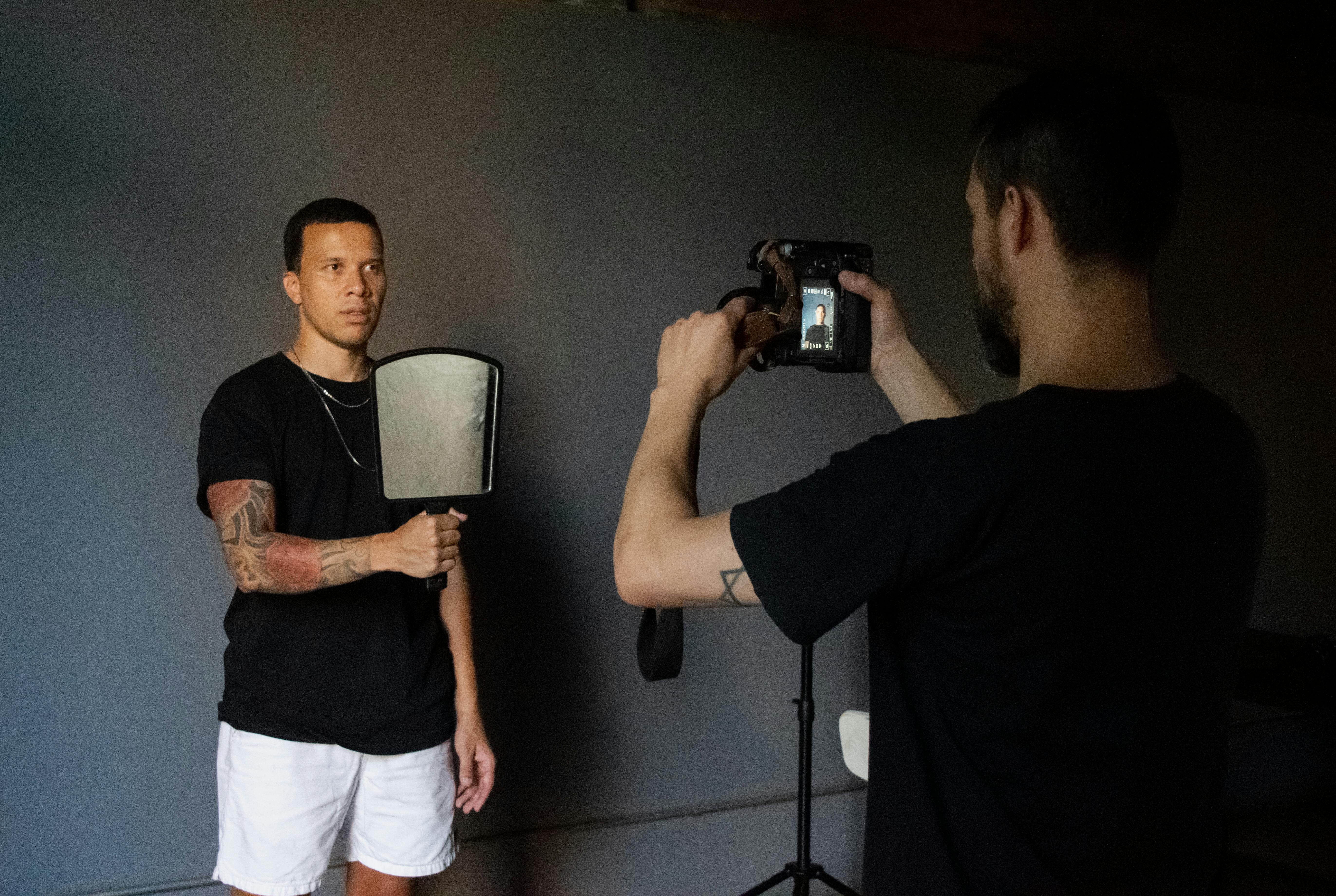 Gratis Un fotografo immortala una modella in uno studio al chiuso con una macchina fotografica. Foto a disposizione