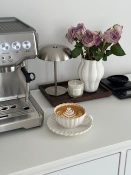 Stylish coffee corner featuring espresso machine, latte art, vase of roses, and cozy candle ambiance.
