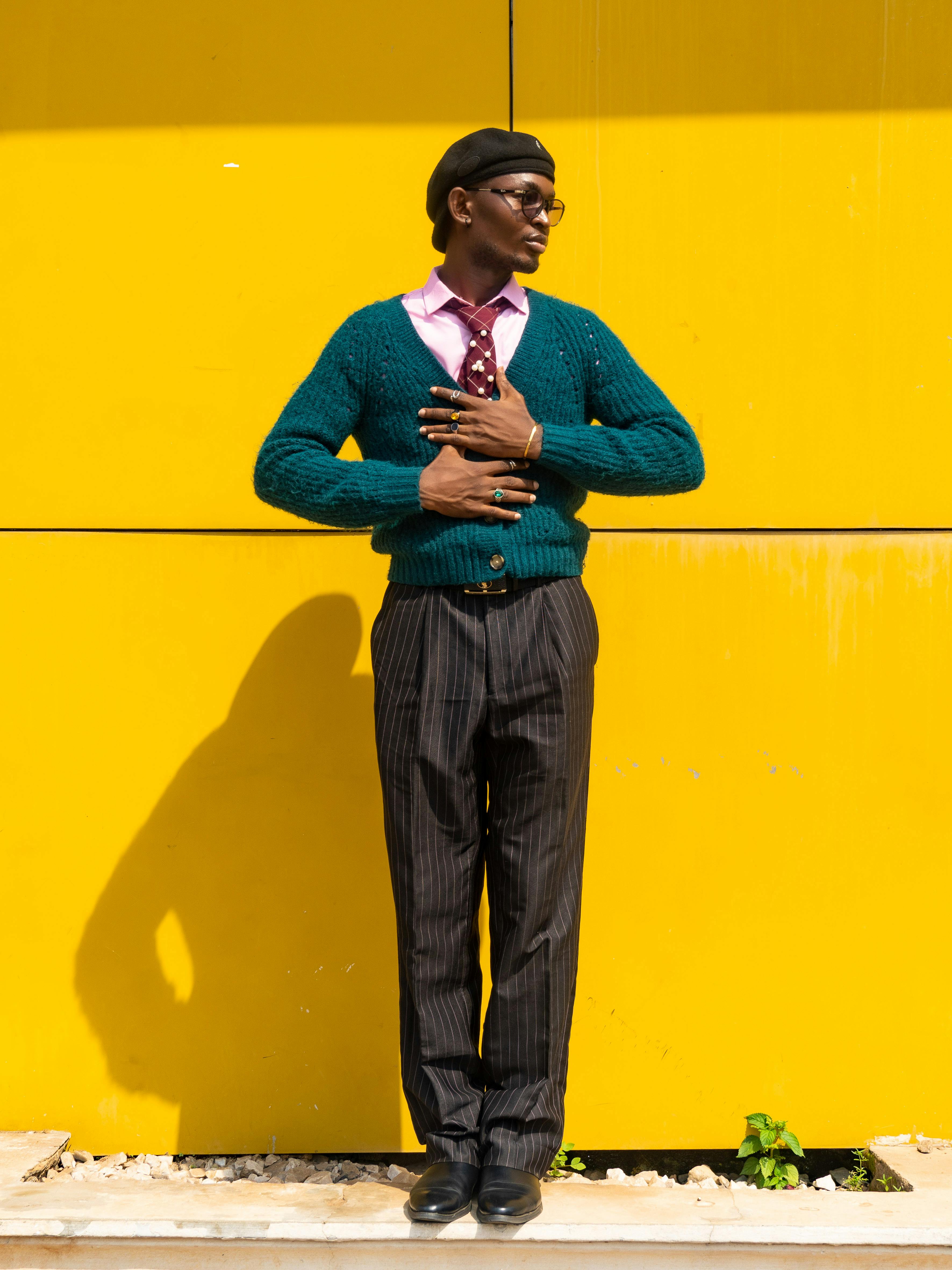 Gratis Un uomo alla moda in un abito colorato posa su uno sfondo giallo brillante ad Abuja. Foto a disposizione