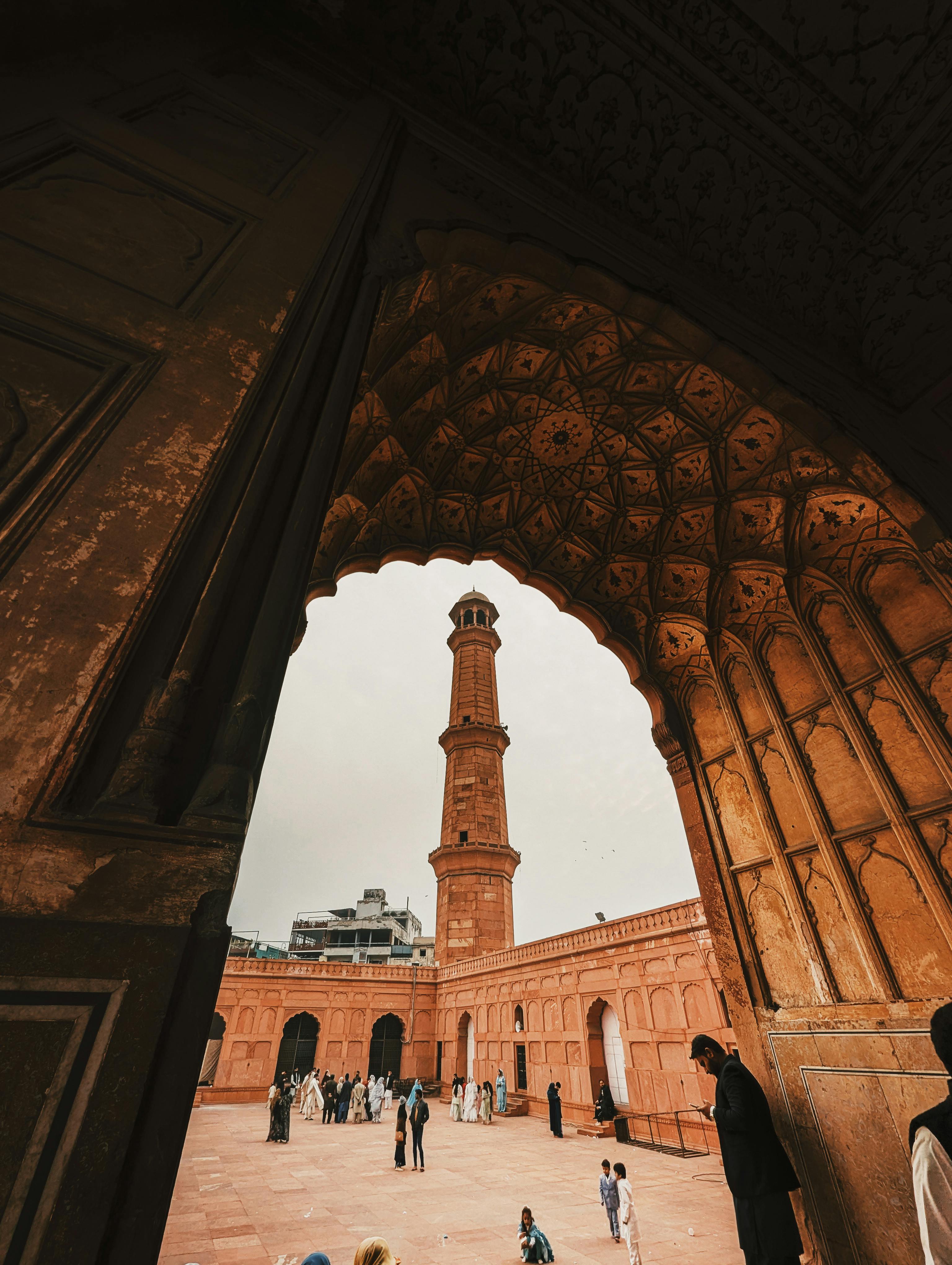 ฟรี ภาพทิวทัศน์อันงดงามของหอคอยมัสยิดที่ล้อมรอบด้วยซุ้มประตูโค้ง พร้อมด้วยผู้เยี่ยมชมที่กำลังสำรวจอยู่ คลังภาพถ่าย