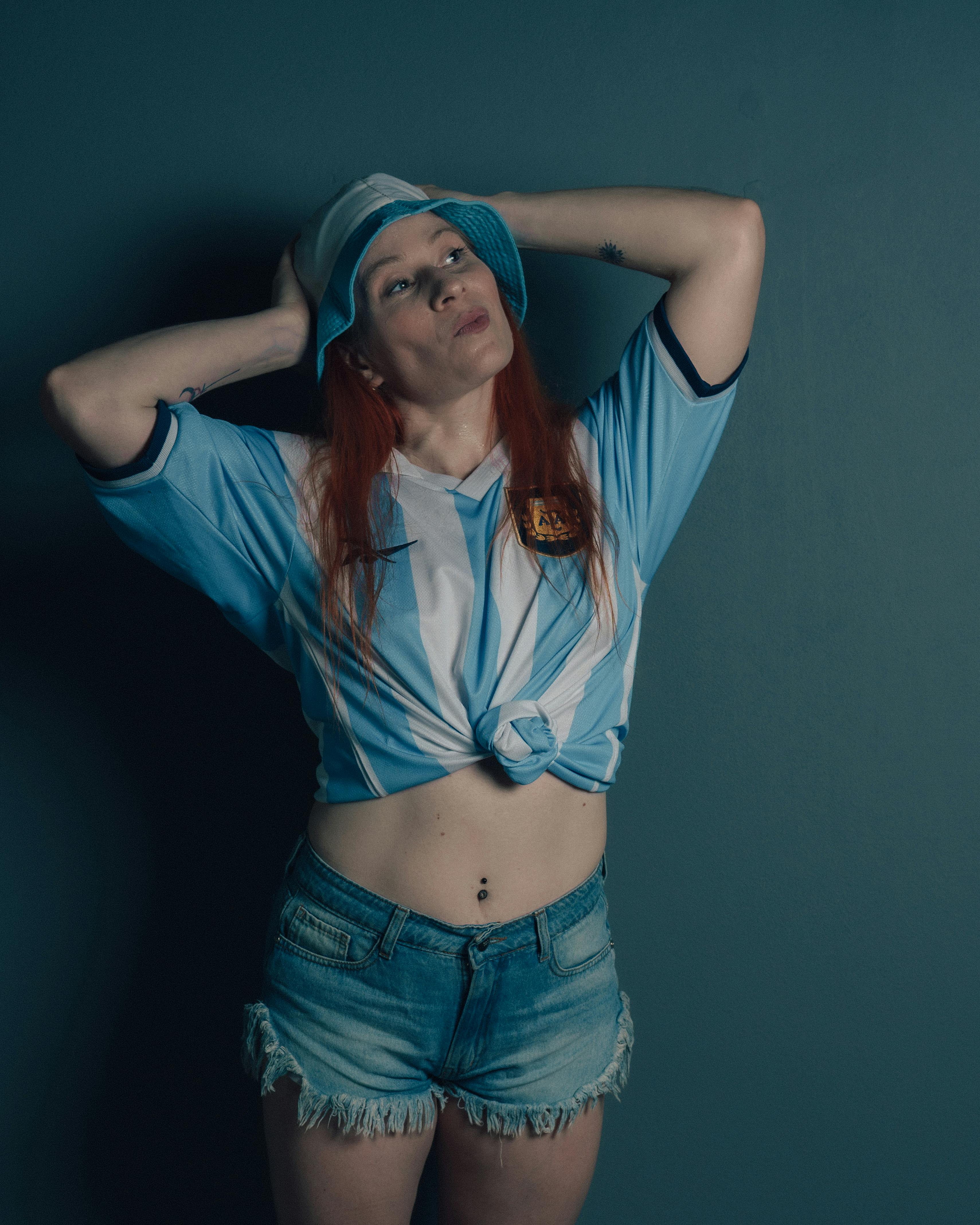 Free Woman wearing soccer jersey and denim shorts, striking a confident pose. Stock Photo