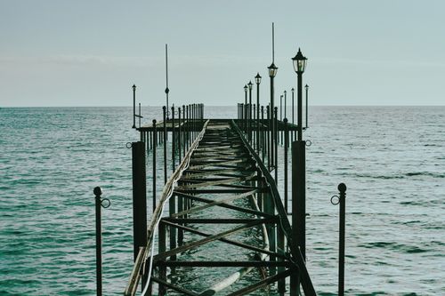 Free A peaceful pier stretches into calm sea under a bright sky, evoking tranquility and freedom. Stock Photo